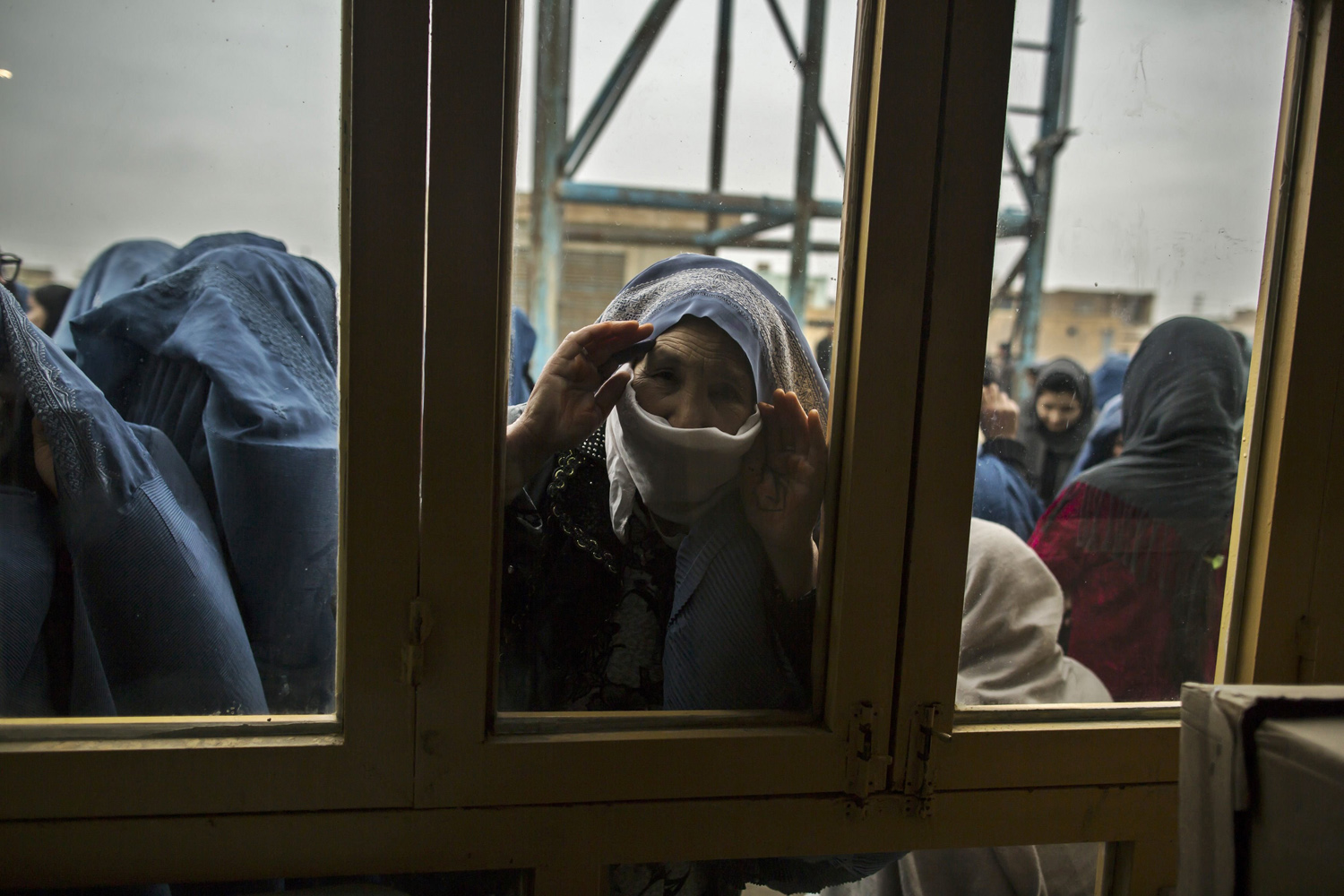 An Afghan woman looks through a window as she waits for her turn to vote at a polling station in Mazar-i-sharif