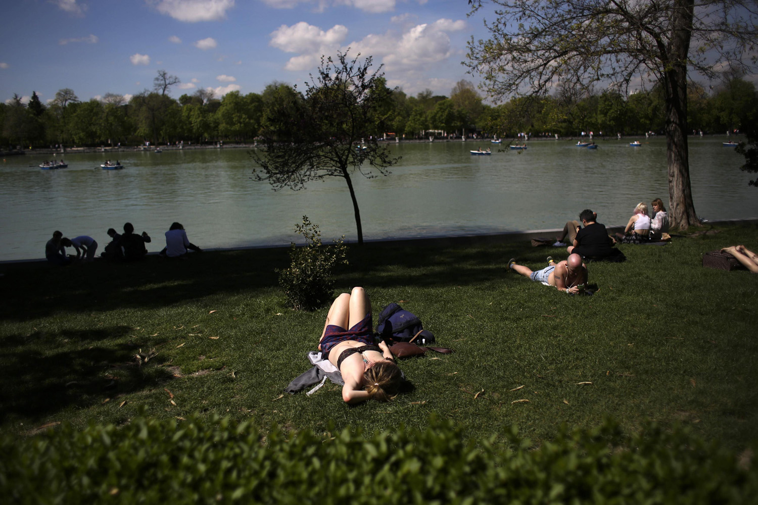 April 7, 2014. People sunbathe and watch boats on an artificial lake as they enjoy the warm weather during a sunny spring day at Madrid's Retiro park in Spain.