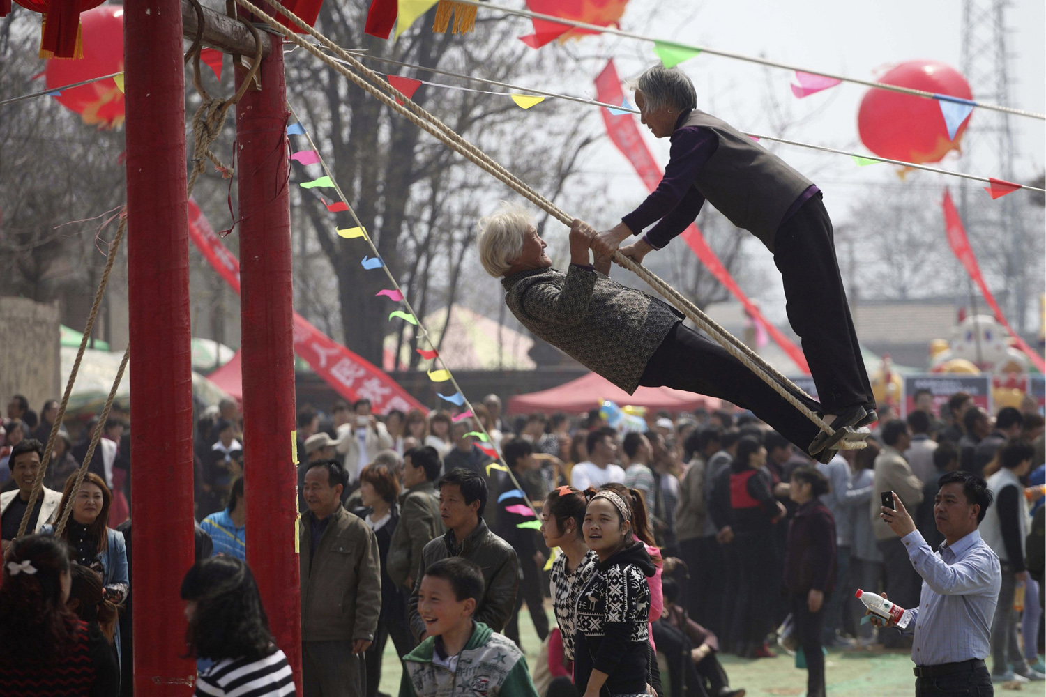 Women play on a swing during a swing festival in Huayin