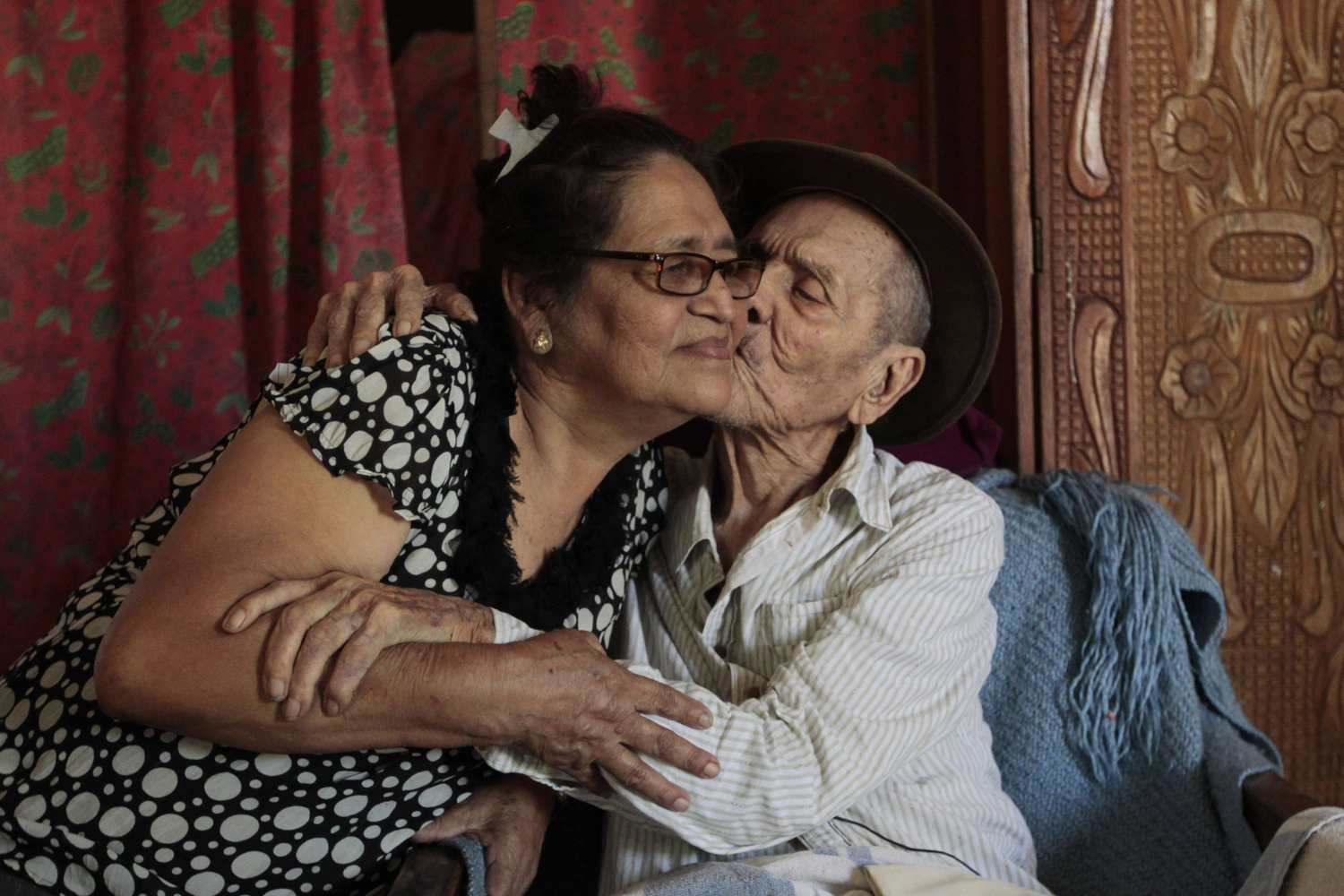 Hector Gaitan, 110, kisses his wife Nora Campo inside his home, at an abandoned station of the Nicaraguan Railway Company, the country's defunct railway in Managua.