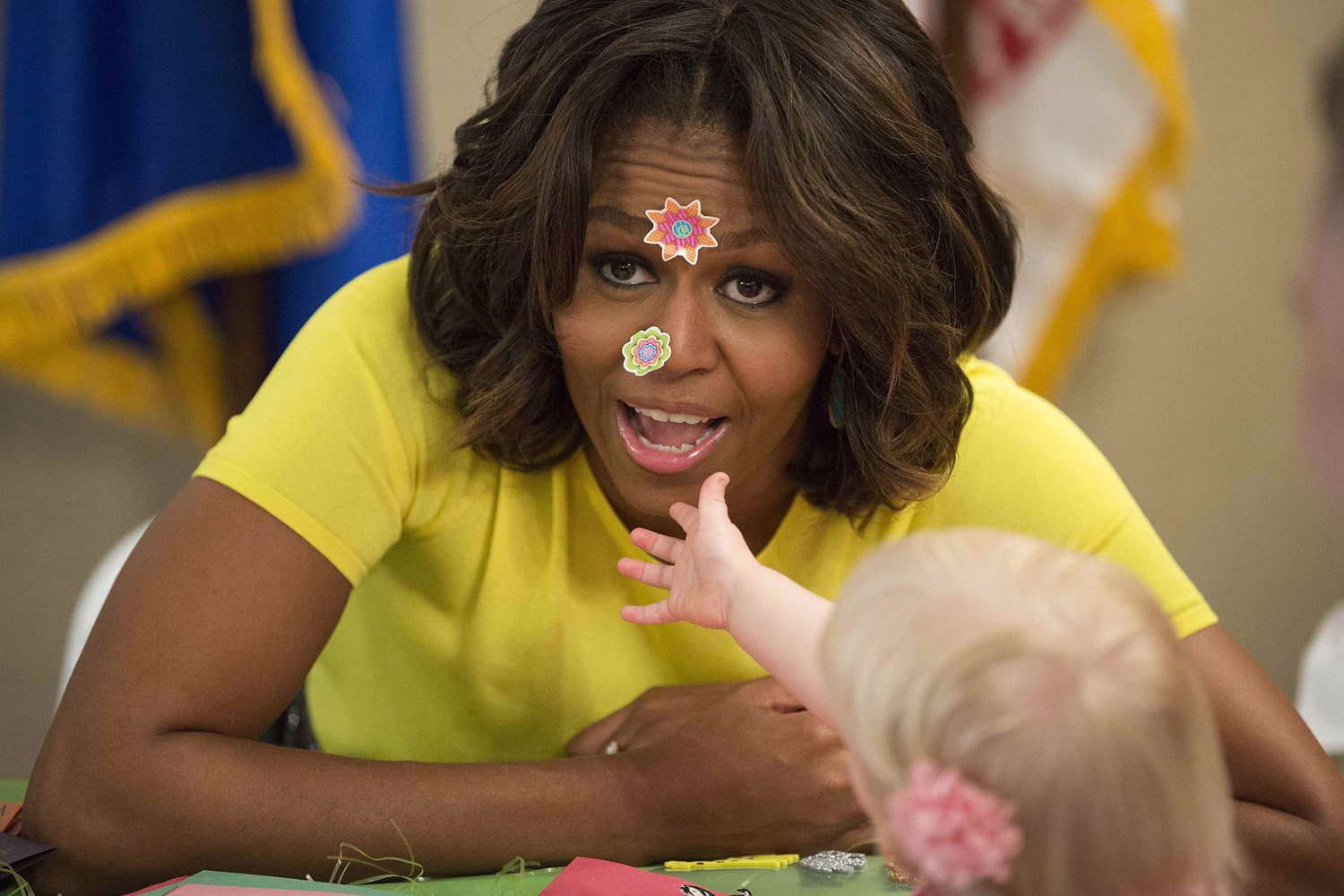 U.S. first lady Michelle Obama has stickers put on her face by 20-month-old Lily Oppelt during a visit with children at the Fisher House at Walter Reed National Military Medical Center in Bethesda, Maryland April 14, 2014.