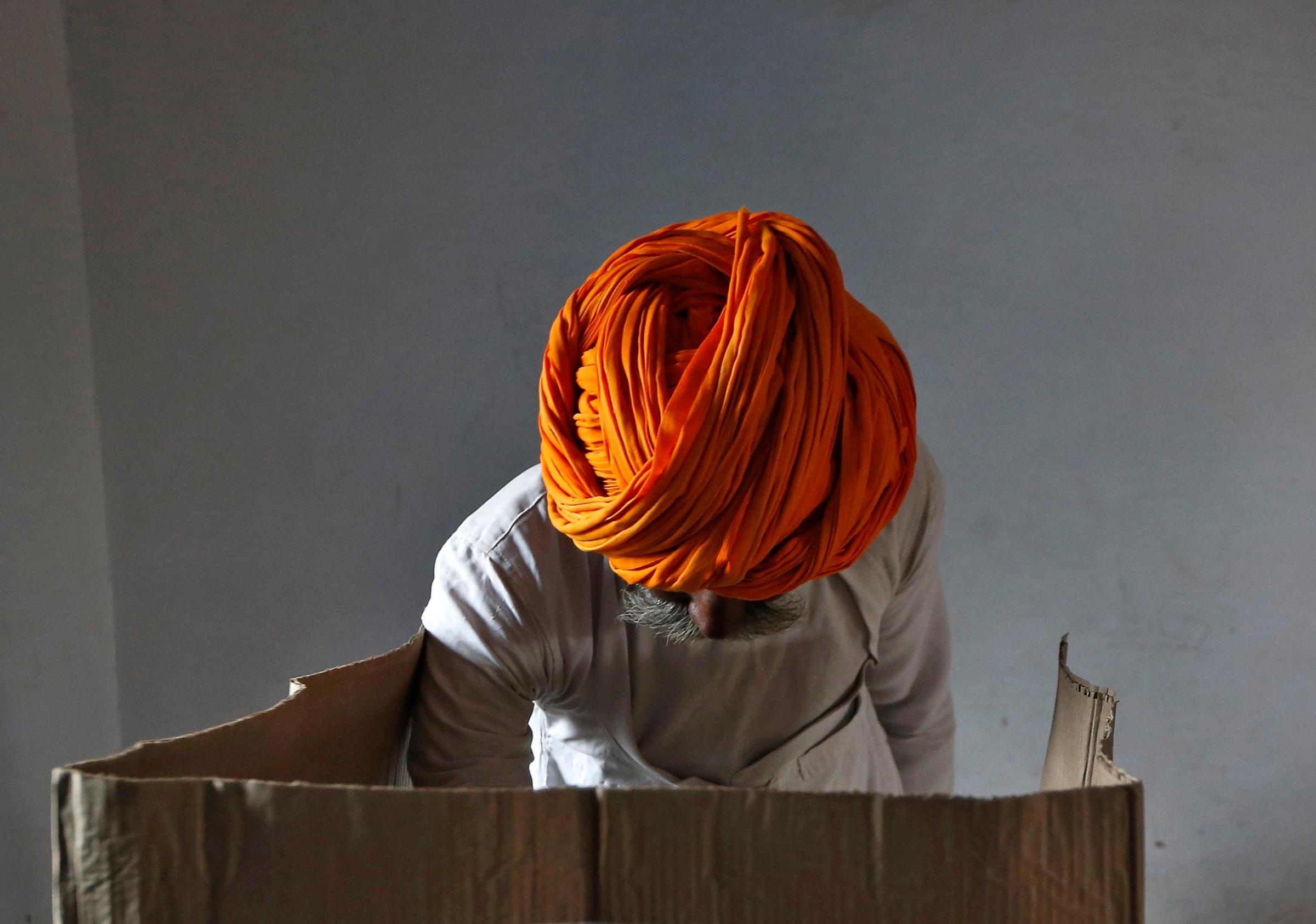 A man wearing a traditional turban casts his vote inside a polling station in Ajmer