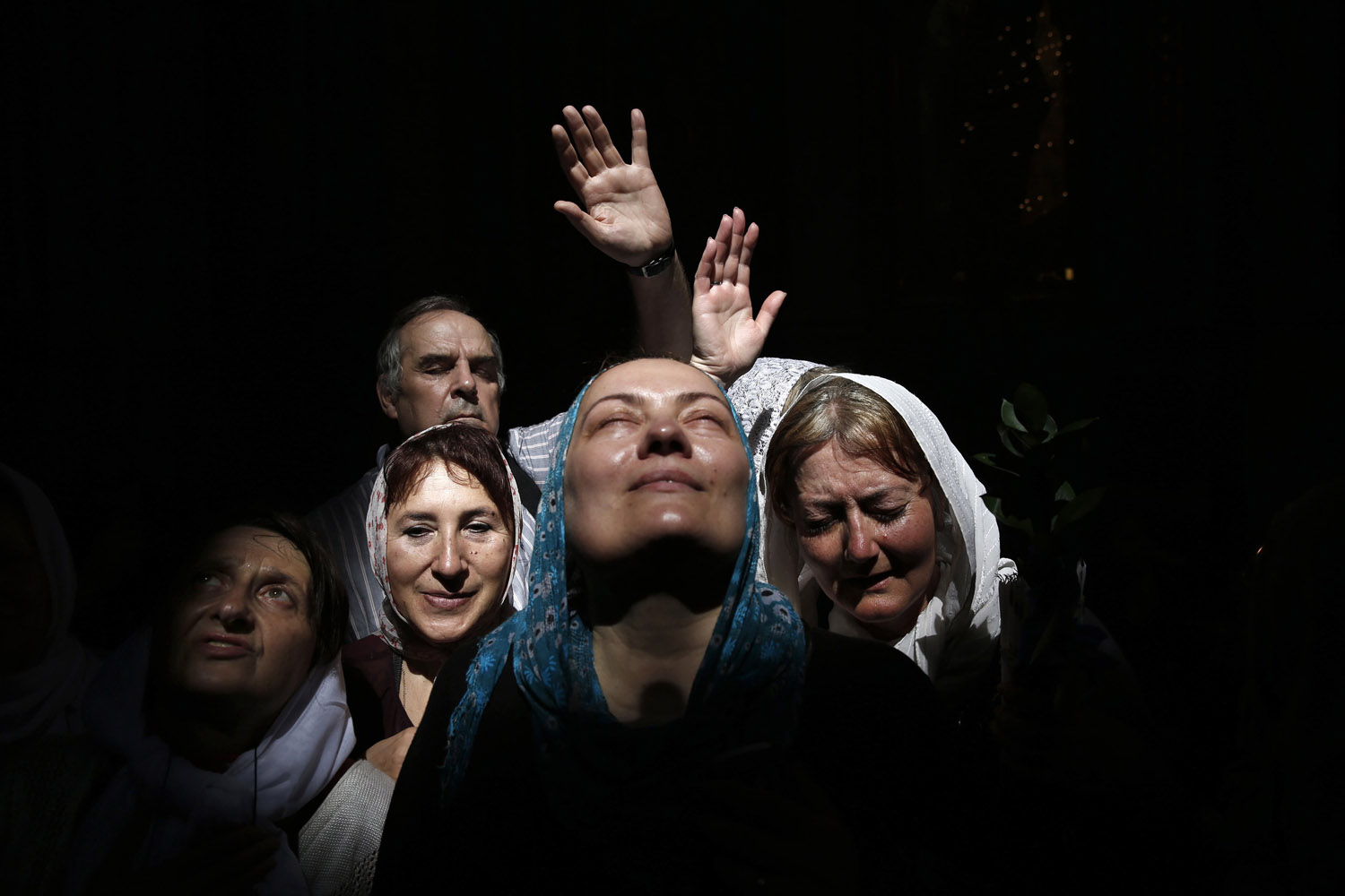 Worshippers react to a beam of sunlight as they take part in the Christian Orthodox Holy Fire ceremony at the Church of the Holy Sepulchre in Jerusalem's Old City