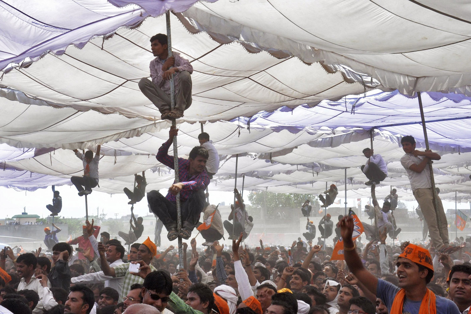 Apr. 21, 2014. Supporters of Hindu nationalist Narendra Modi, the prime ministerial candidate for India's main opposition Bharatiya Janata Party (BJP), climb over the poles of a temporary tent to get a glimpse of Modi during an election campaign rally at Mathura in the northern Indian state of Uttar Pradesh.
