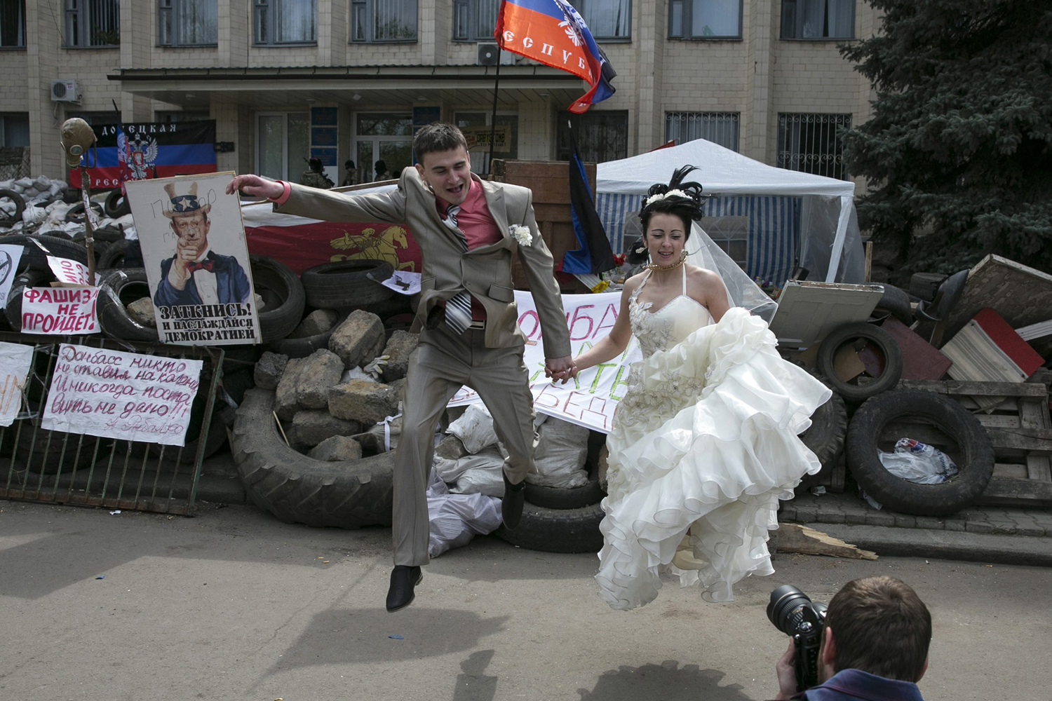 A pair of bride and groom jumps in front of barricades outside a regional government building seized by pro-Russian armed men in Kramatorsk
