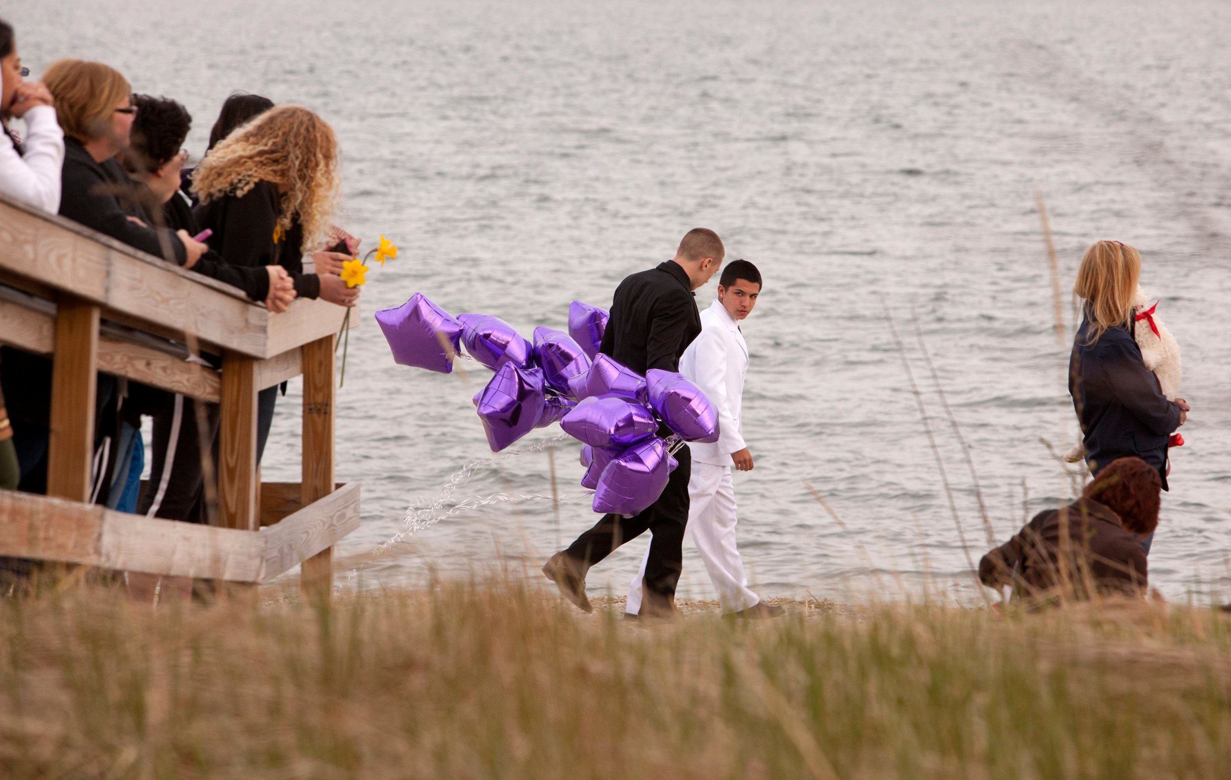 Students arrive at beach for vigil in honor of slain student Sanchez wearing prom clothes carrying balloons in Milford