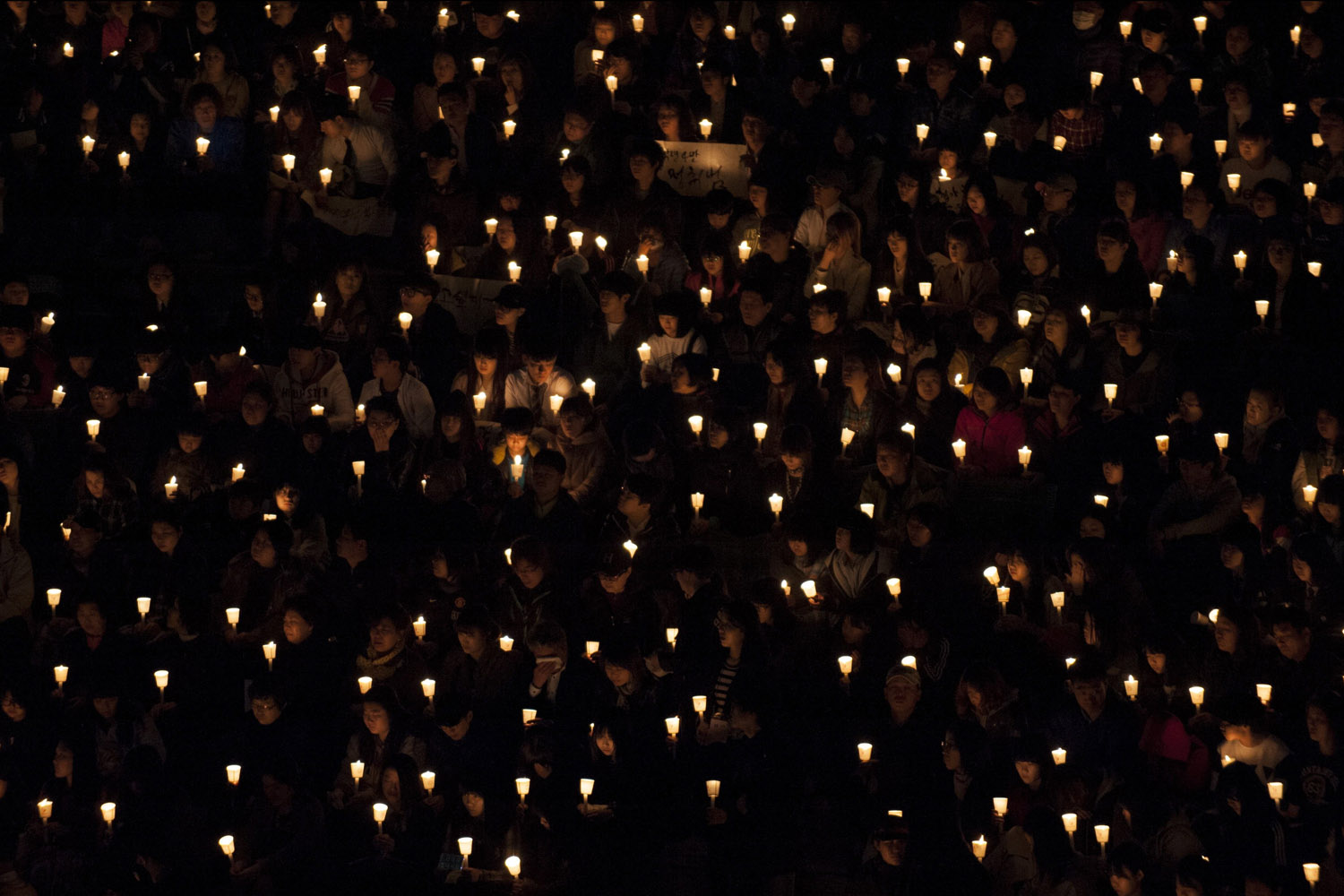 Apr. 19, 2014. People hold candles during a vigil in Ansan. Students, parents, teachers, and others from the community gathered at a park near Danwon High School to pray for the missing and mourn the dead from the Sewol ferry sinking.