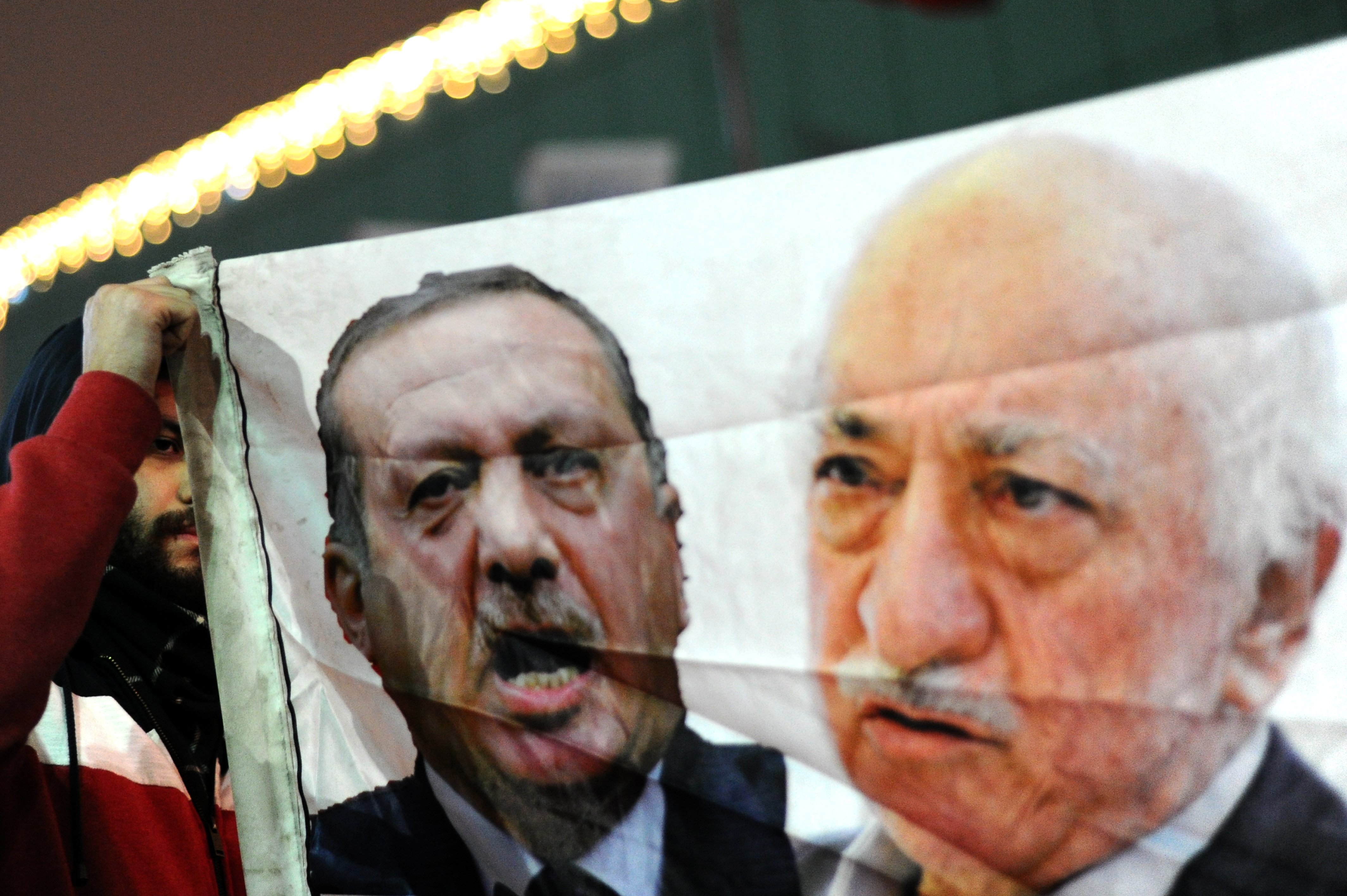 A Turkish protester (L) holds up a banner with pictures of Turkish Prime Minister Recep Tayyip Erdogan (C) and the United States-based Turkish cleric Fethullah Gulen (R) during a demonstration against goverment on December 30, 2013 in Istanbul. (Ozan Kose—AFP/Getty Images)