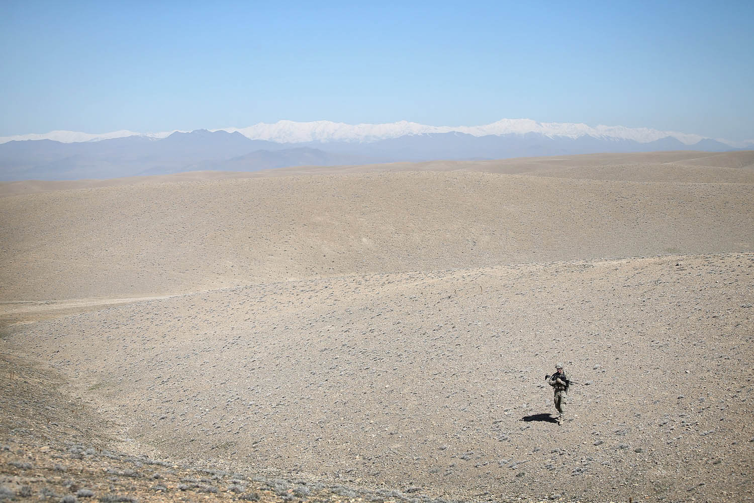 Mar. 30, 2014.  SGT Martyn Piggott from Pittstown, New Jersey with the U.S. Army's 2nd Battalion 87th Infantry Regiment, 3rd Brigade Combat Team, 10th Mountain Division patrols across barren foothills looking for positions the enemy has used to send rockets onto the FOB near Pul-e Alam, Afghanistan.