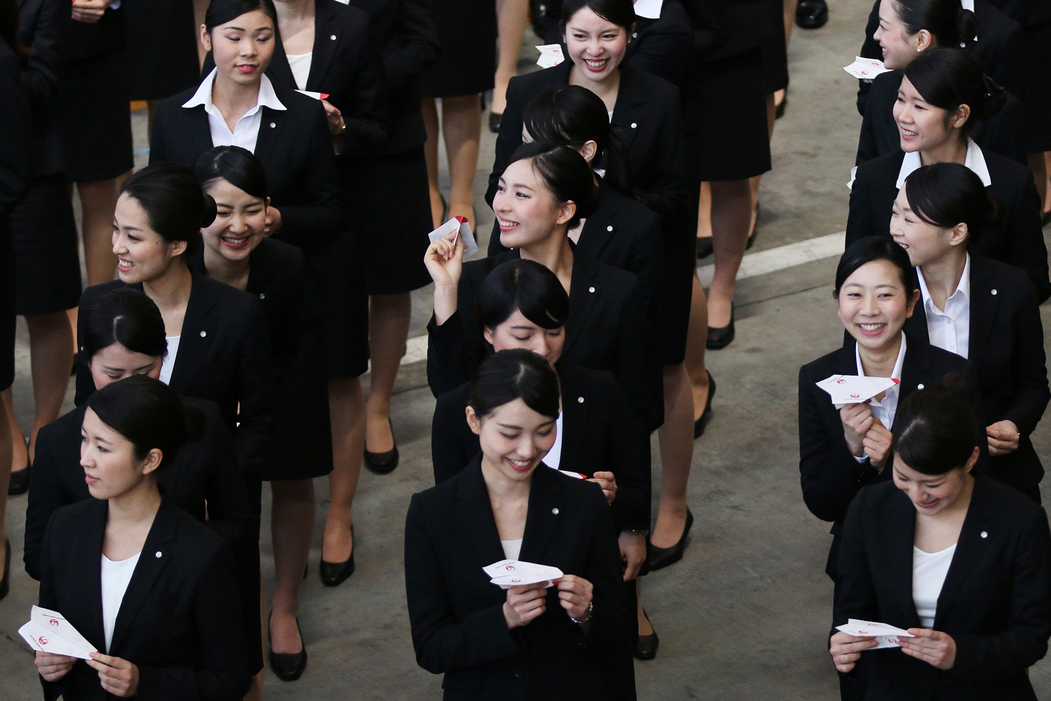 New employees to Japan Airlines Company prepare to release paper planes during a welcoming ceremony at the company's hangar near Haneda Airport in Tokyo on April 1, 2014.
