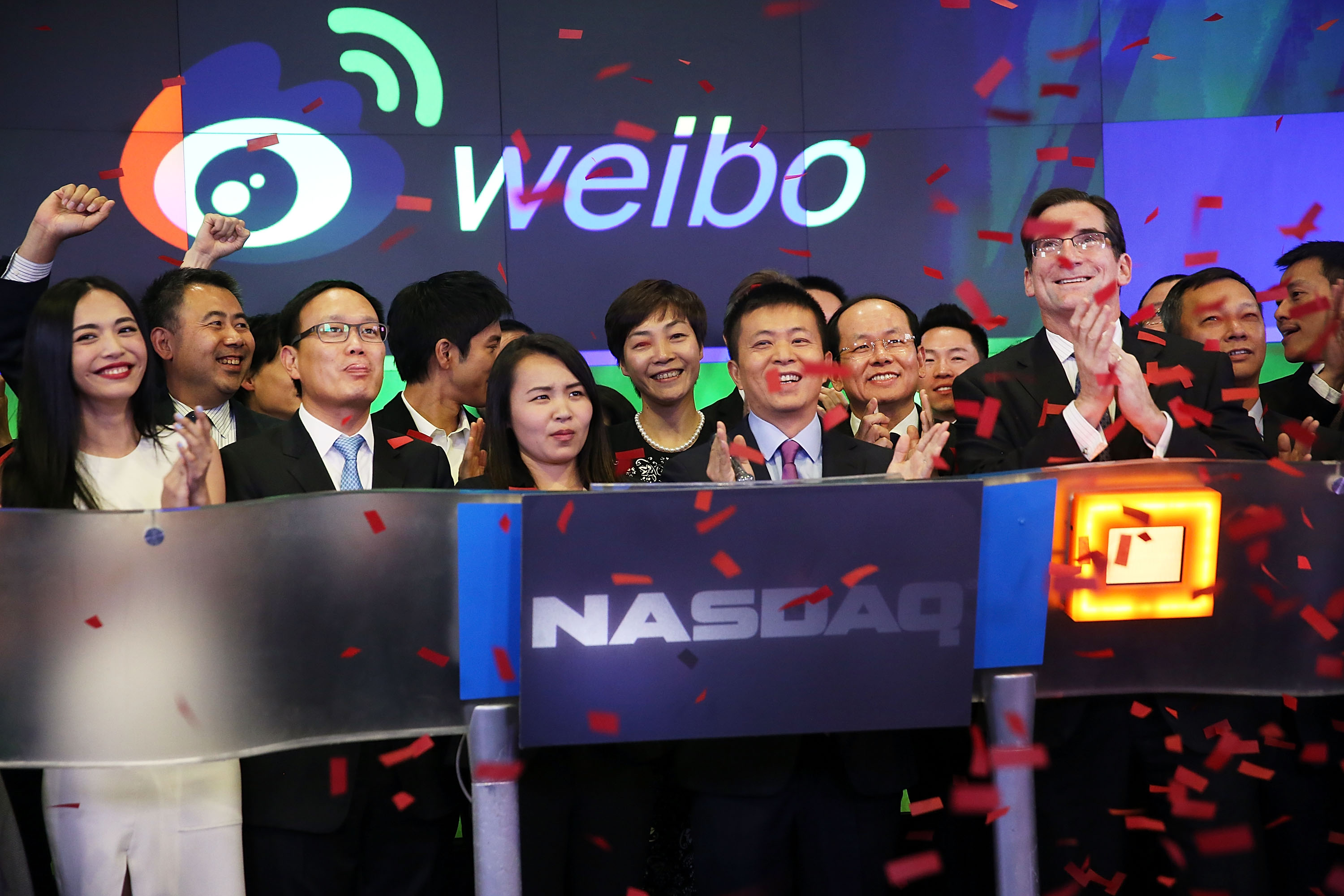 China's Weibo CEO Charles Chao (center) stands with Robert Greifeld, Nasdaq CEO, moments after Weibo began trading on the Nasdaq exchange under the ticker symbol WB on April 17, 2014 in New York City. (Spencer Platt—Getty Images)