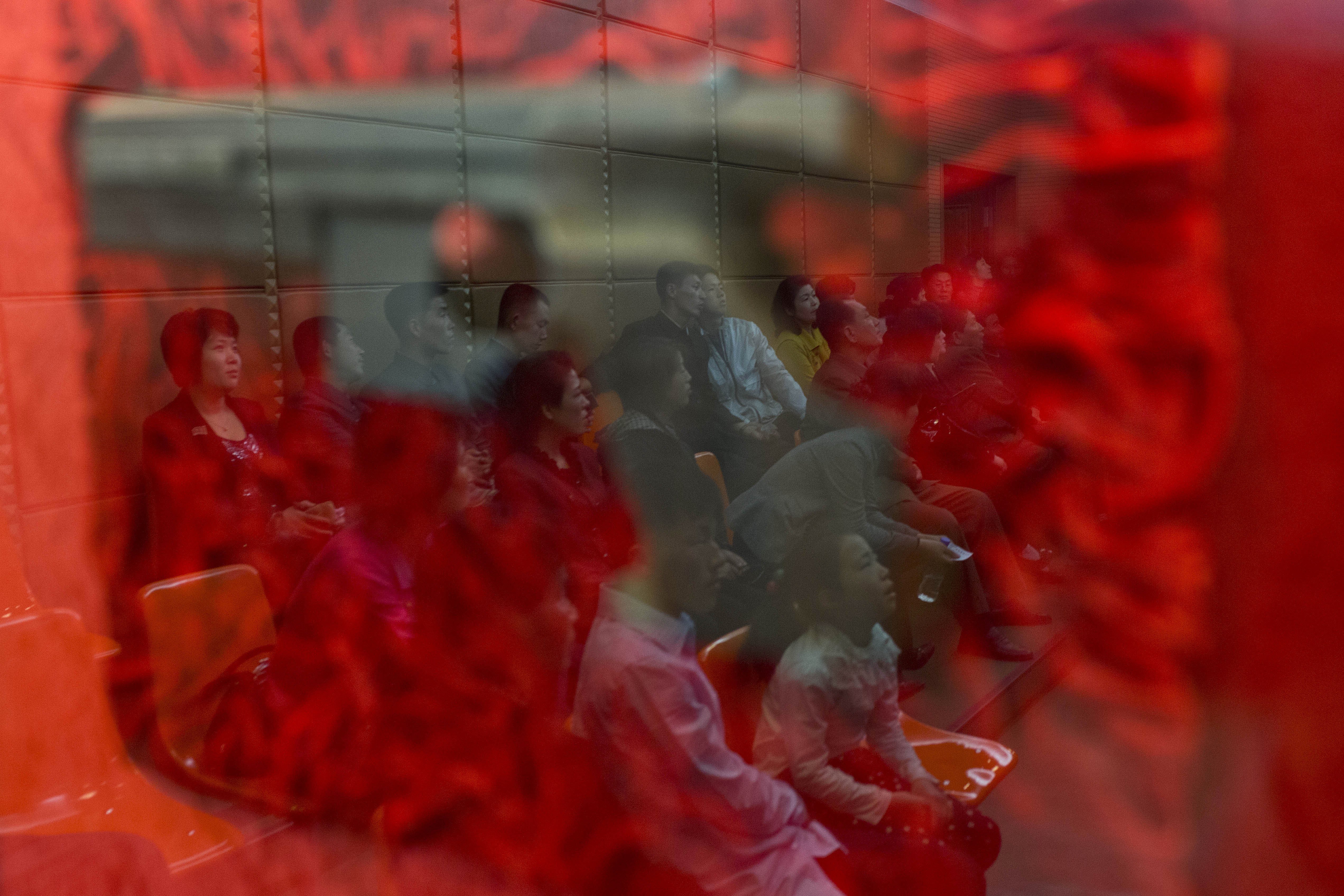 Apr. 16, 2014. North Koreans are reflected in a glass case containing a pistol as they each wait for their turn at a firing range at the Meari Shooting Gallery in Pyongyang. Employees at the firing range said the pistol on display had been used by North Korean leaders Kim Jong Il and Kim Jong Un when each toured the facility in the past.