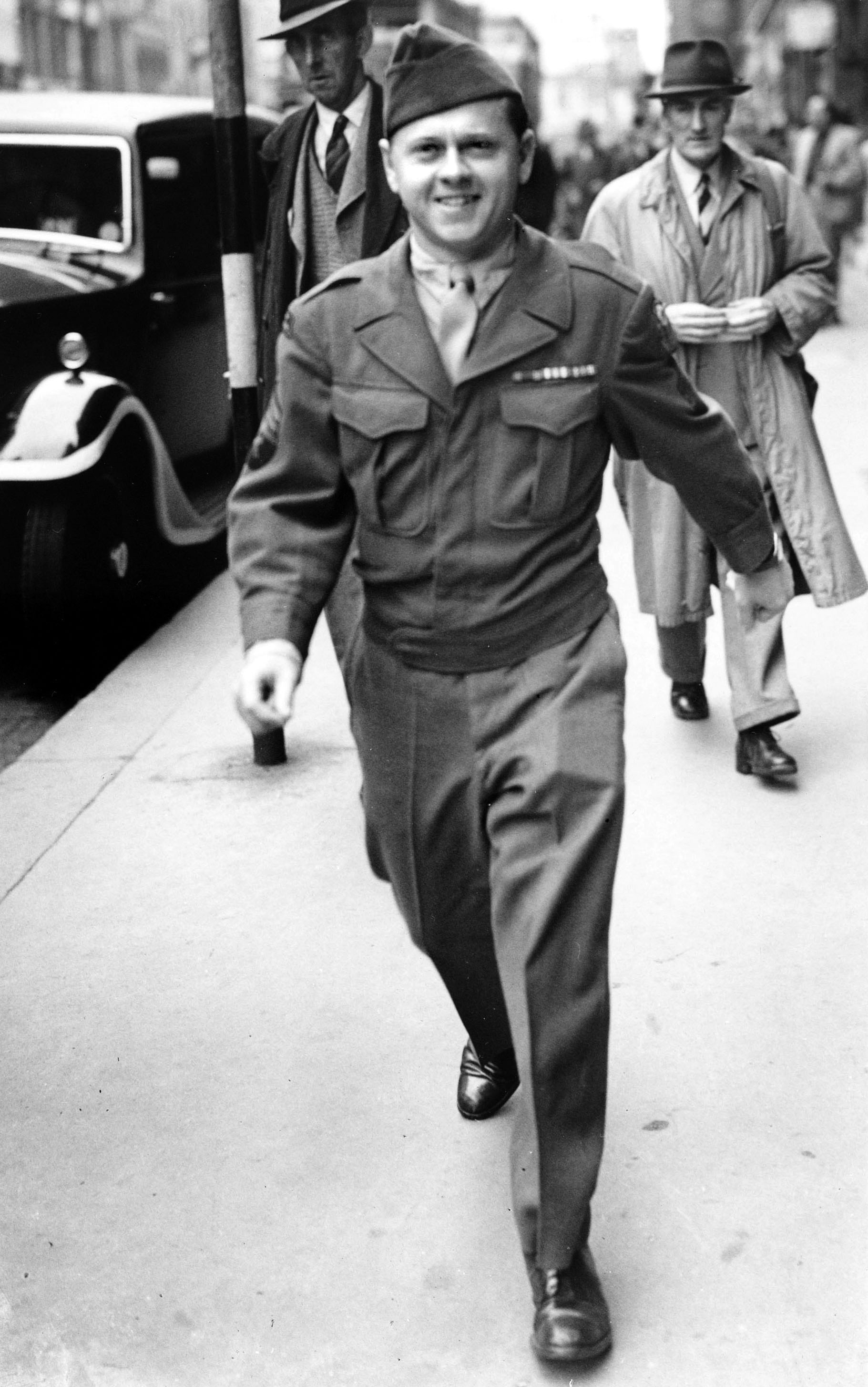 World War II, London, England, 11th August 1945, American film actor and army sergeant Mickey Rooney walks down a pavement watched by bystanders