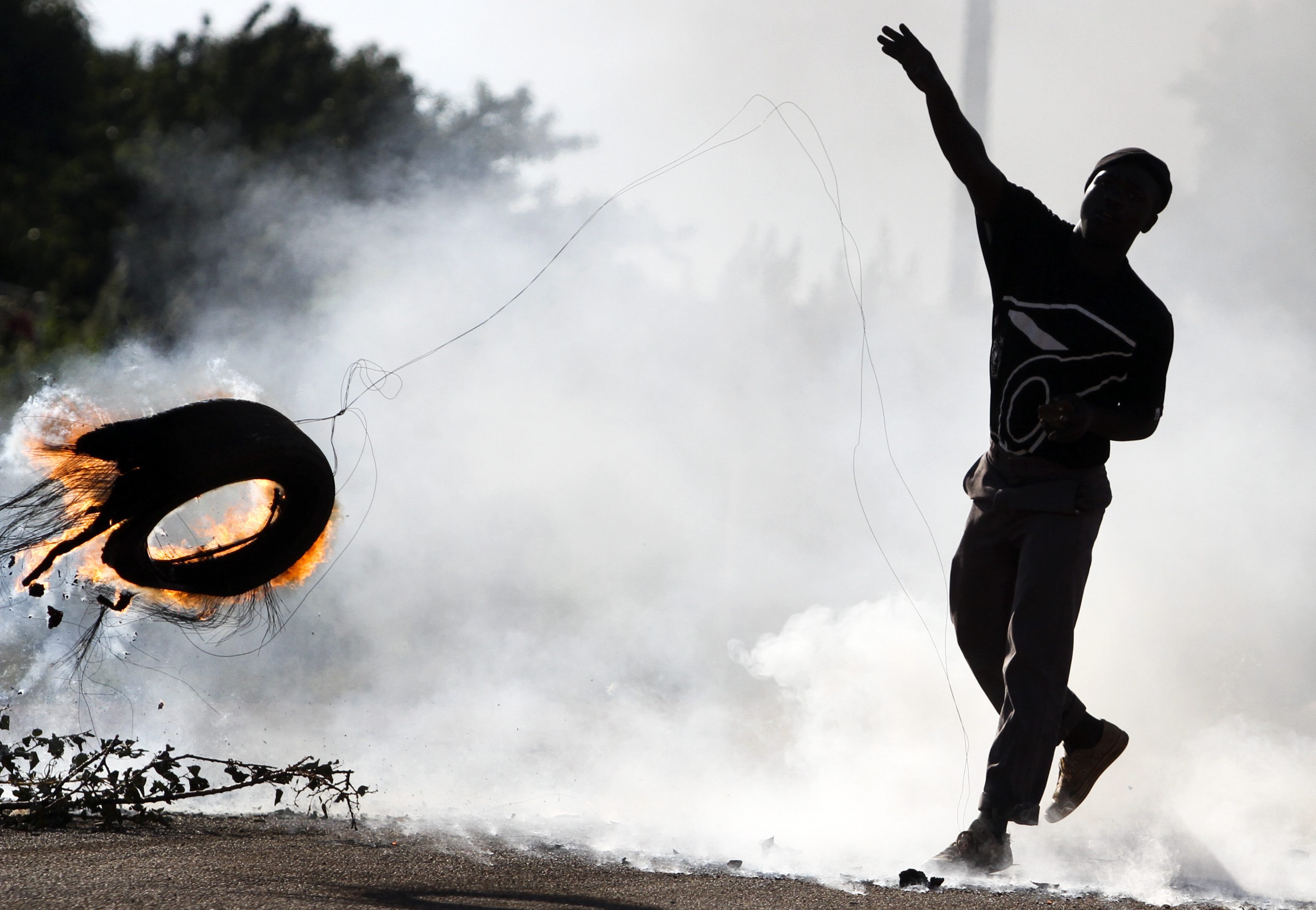 A South African man hurls a burning tire in Johannesburg during protests over squalid living conditions in 2010. Conditions for the poor are worsening around the world (Gallo Images&mdash;Getty Images)