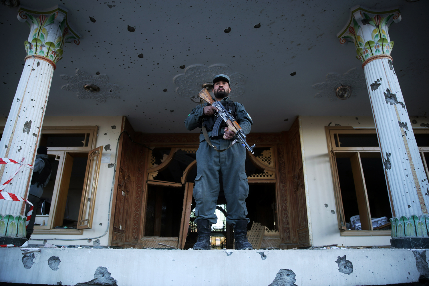 An Afghan policeman stands guard in front of an Independent Elections Commission (IEC) building after a gun battle between security forces and insurgents in Kabul, Afghanistan, Tuesday, March 25, 2014. (Massoud Hossaini - AP)