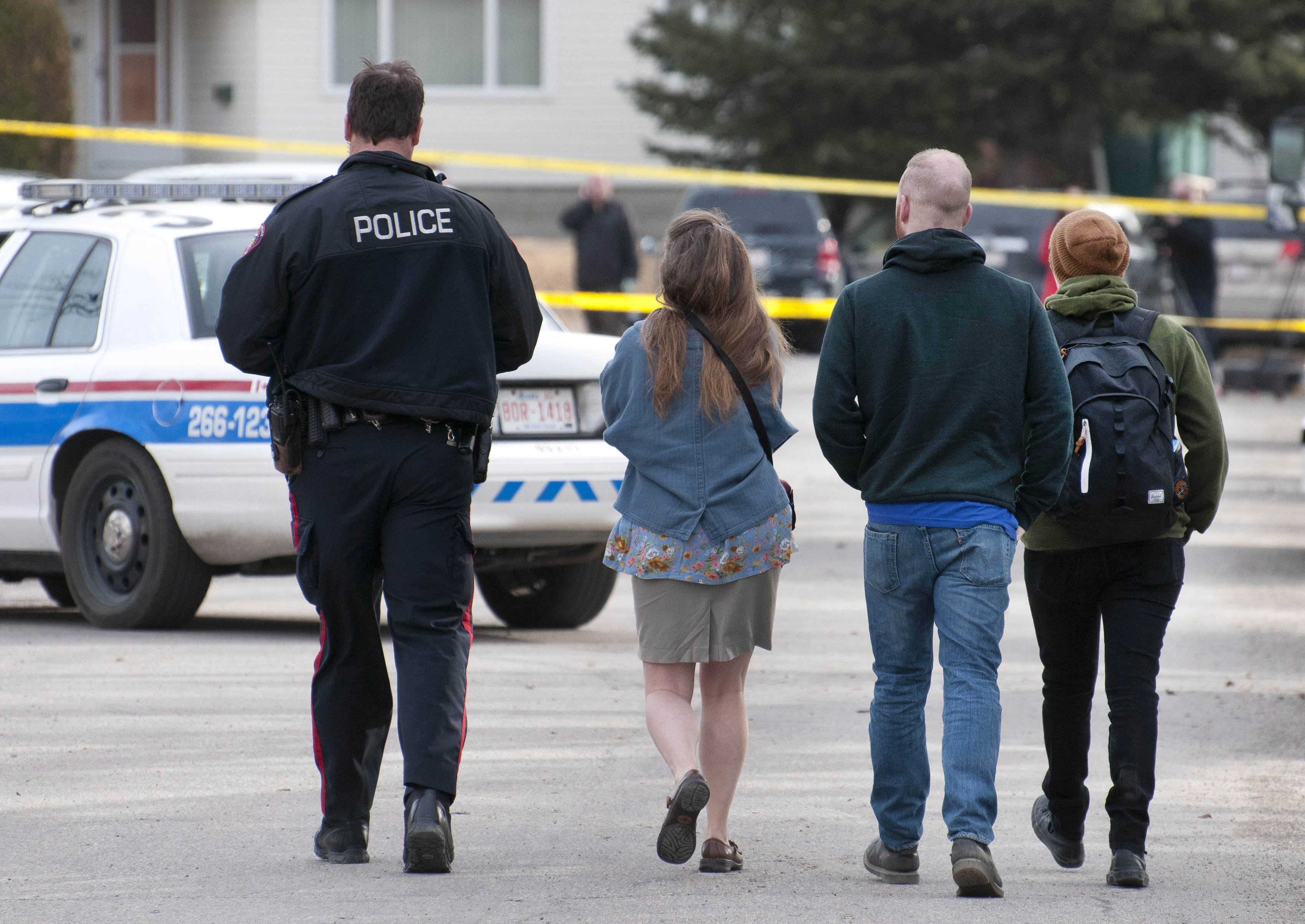 Calgary police lead away potential witnesses for statements regarding the multiple fatal stabbing in northwest Calgary, Canada, on April 15, 2014 (Larry MacDougal—The Canadian Press/AP)