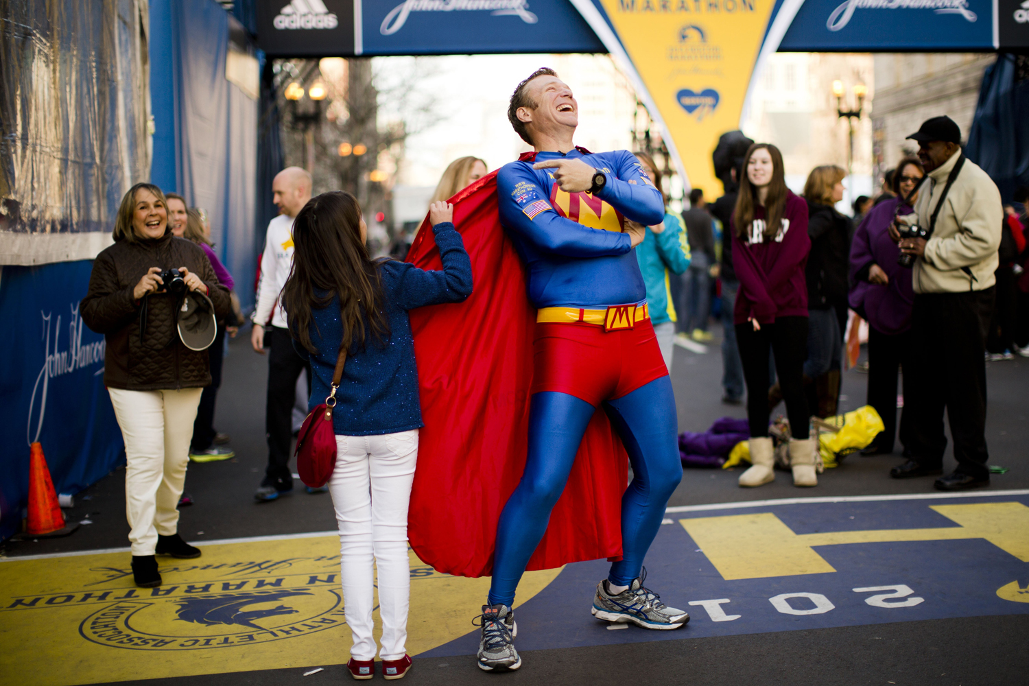Trent Morrow of Sydney, Australia, also know as "Marathon Man" laughs as Andrea Olivo of Venezuela tugs on his cape as she has her photo made ahead of Monday's 118th Boston Marathon, Sunday, April 20, 2014. (Mosa'ab Elshamy)