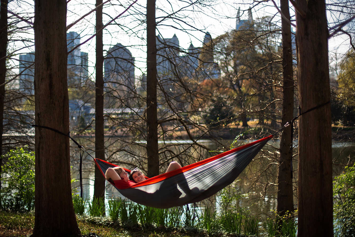 From left, Chris Hoag and Parrish Brown sit in a hammock they put up along the pond in Piedmont Park in Atlanta April 1, 2014.