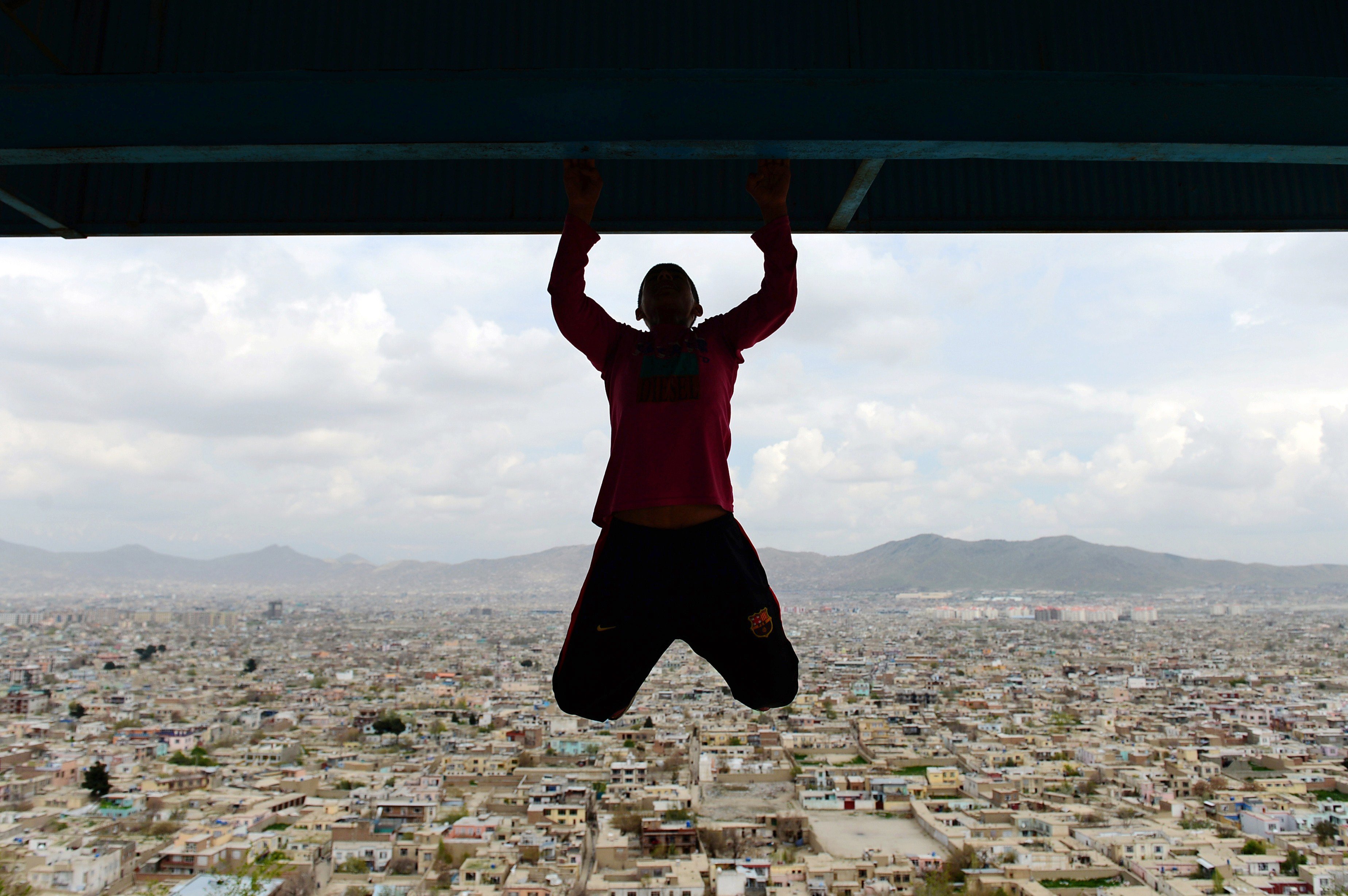 April 18, 2014. An Afghan youth exercises at Wazir Akbar Khan hilltop overlooking Kabul. Football is a popular sport in the war-torn country, with the Afghan national football team winning last year's South Asian Football Championship.