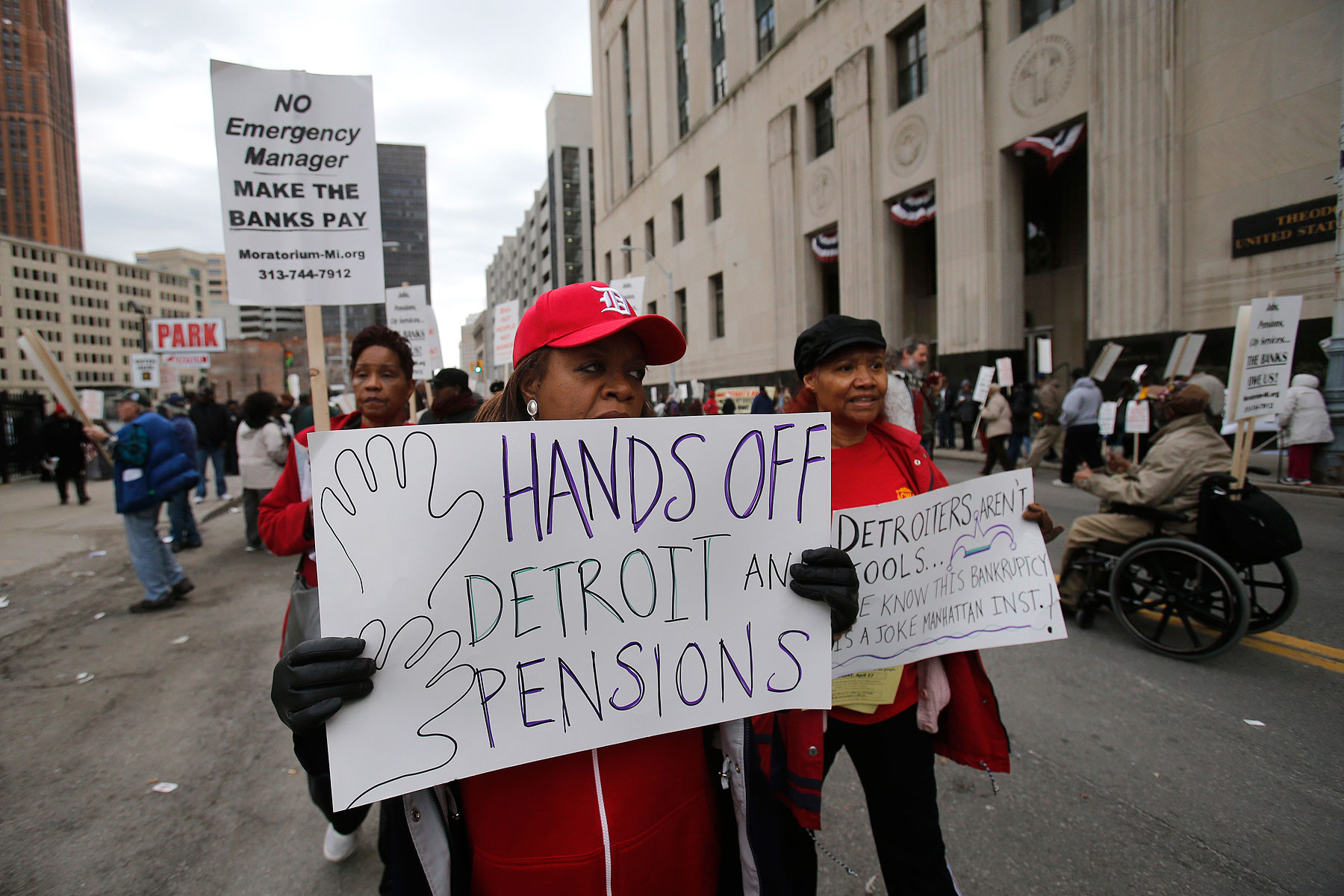 A protestor holds a sign outside the federal courthouse in support of Detroit city workers (Rebecca Cook—Reuters)