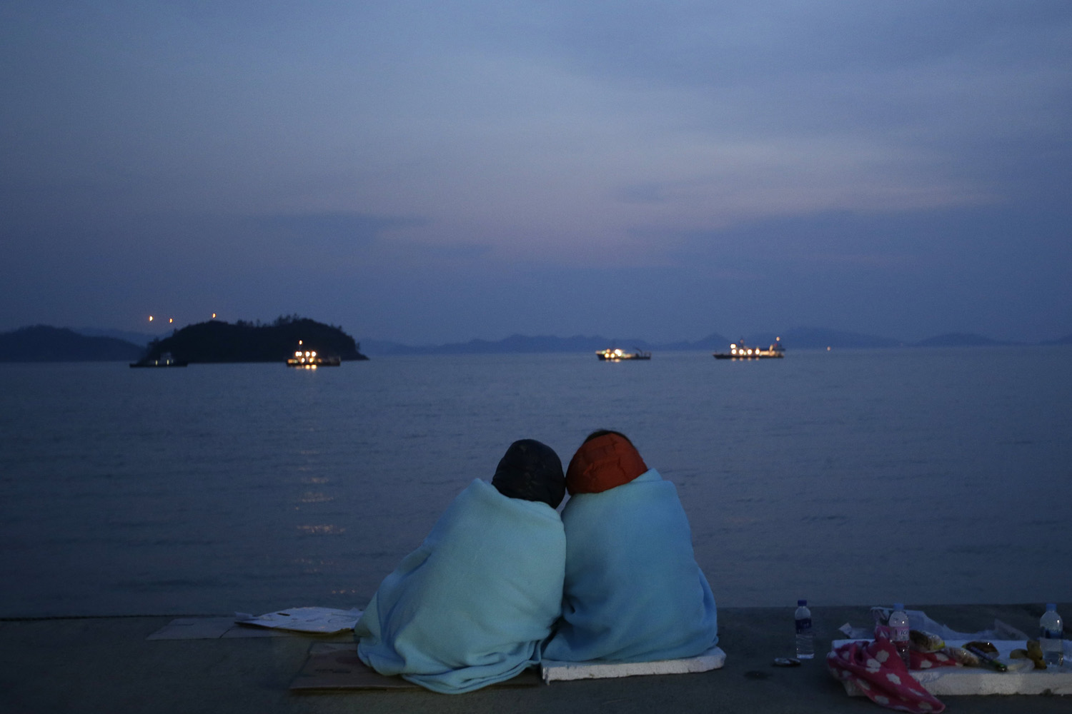 Apr. 20, 2014. Relatives of passengers aboard the sunken ferry Sewol sit near the sea at a port in Jindo, south of Seoul, South Korea. After more than three days of frustration and failure, divers on Sunday finally found a way into the submerged ferry off South Korea's southern shore, discovering more than a dozen bodies inside the ship.