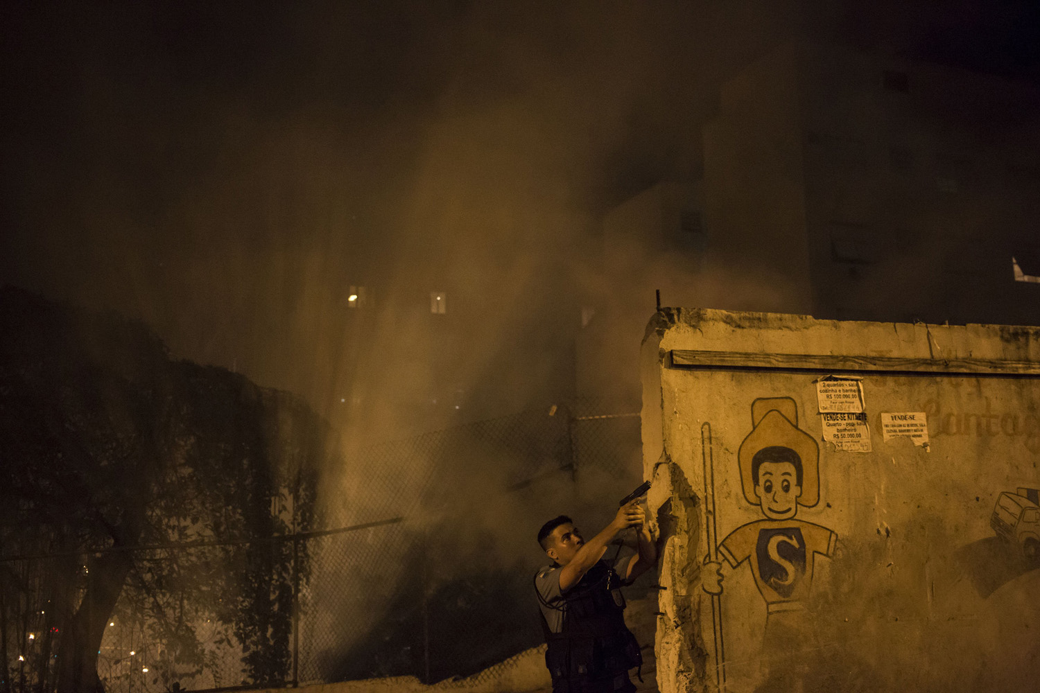 Apr. 22, 2014. A Police officer of the Pacifying Police Unit, patrols among the smoke from burning barricades during clashes at the Pavao Pavaozinho slum in Rio de Janeiro, Brazil.