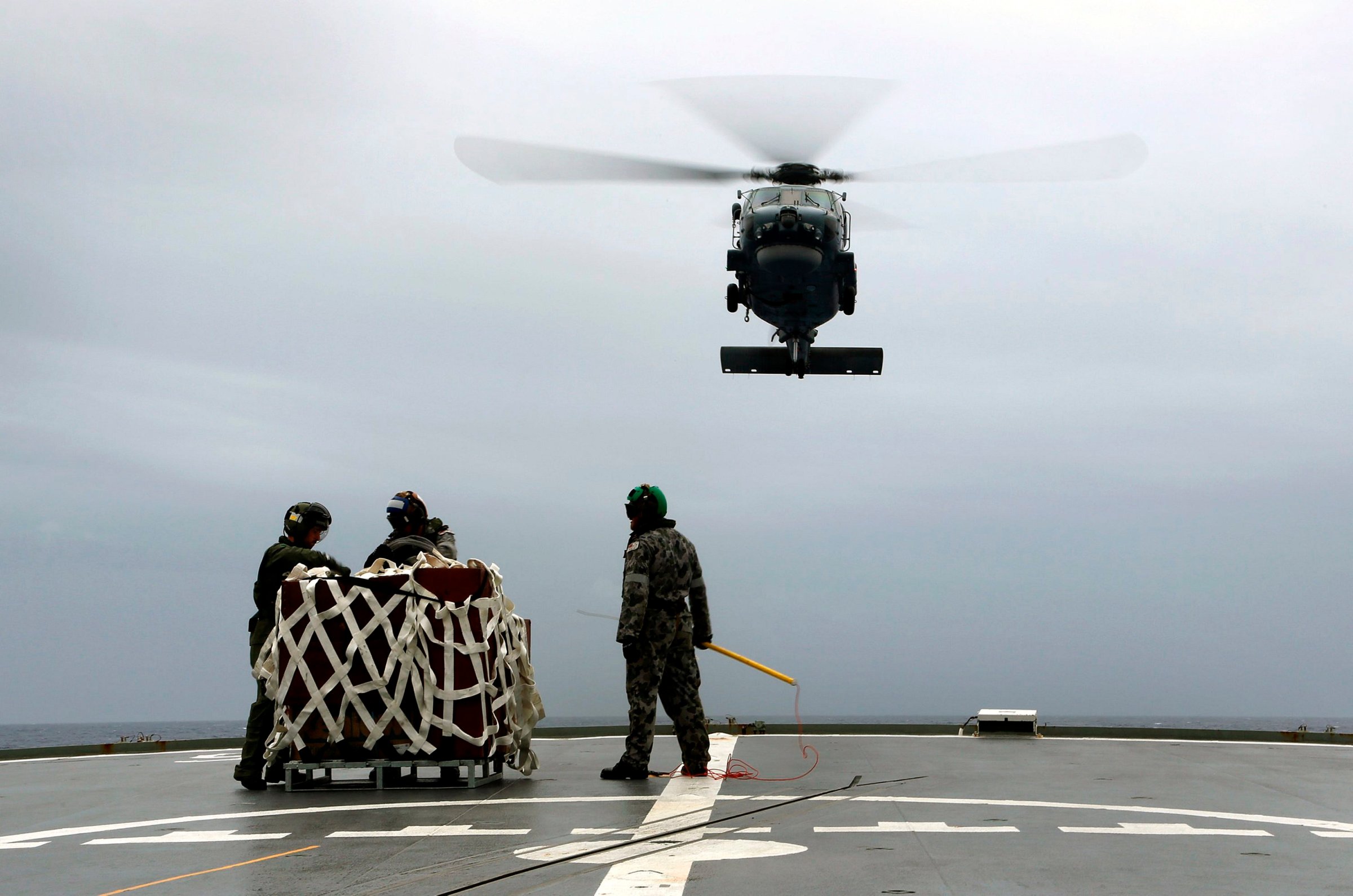 A S-70B-2 Seahawk (Tiger 75) helicopter approaches the flight deck of Australian Navy ship HMAS Toowoomba to pick up supplies during a vertical replenishment at sea with HMAS Success as they continue to search for the missing Malaysian Airlines flight MH370 in this picture released by the Australian Defence Force April 6, 2014.
