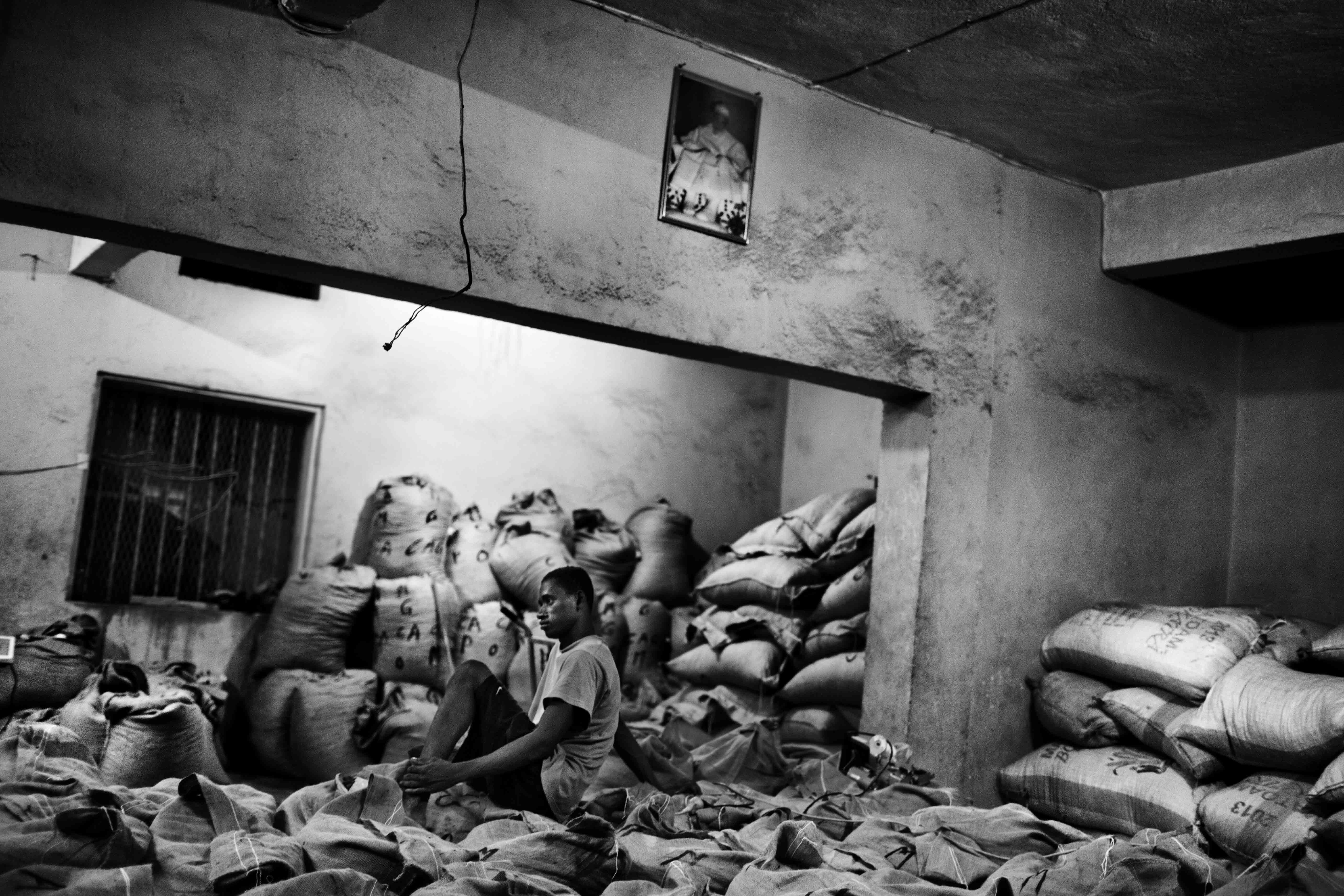 A man named Hashis sits on top of a new shipment of cocoa beans from the farmers who work for him. Aug, 7, 2013.