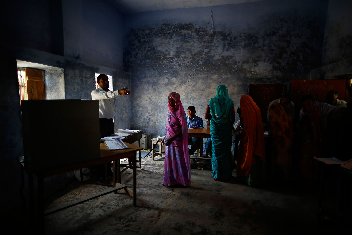 A woman voter is guided by an officer at a polling booth in Ujina, Haryana, India on April 10, 2014 for the crucial third phase of national elections.