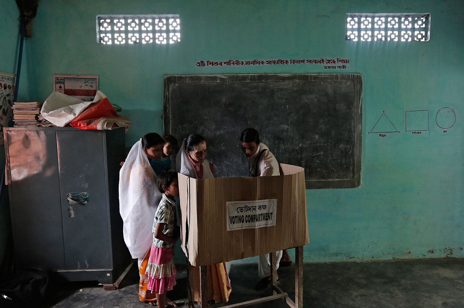A polling officer helps a woman to cast her vote at a polling station in Majuli, a large river island in the Brahmaputra river, Jorhat district, in the northeastern Indian state of Assam, April 7, 2014.