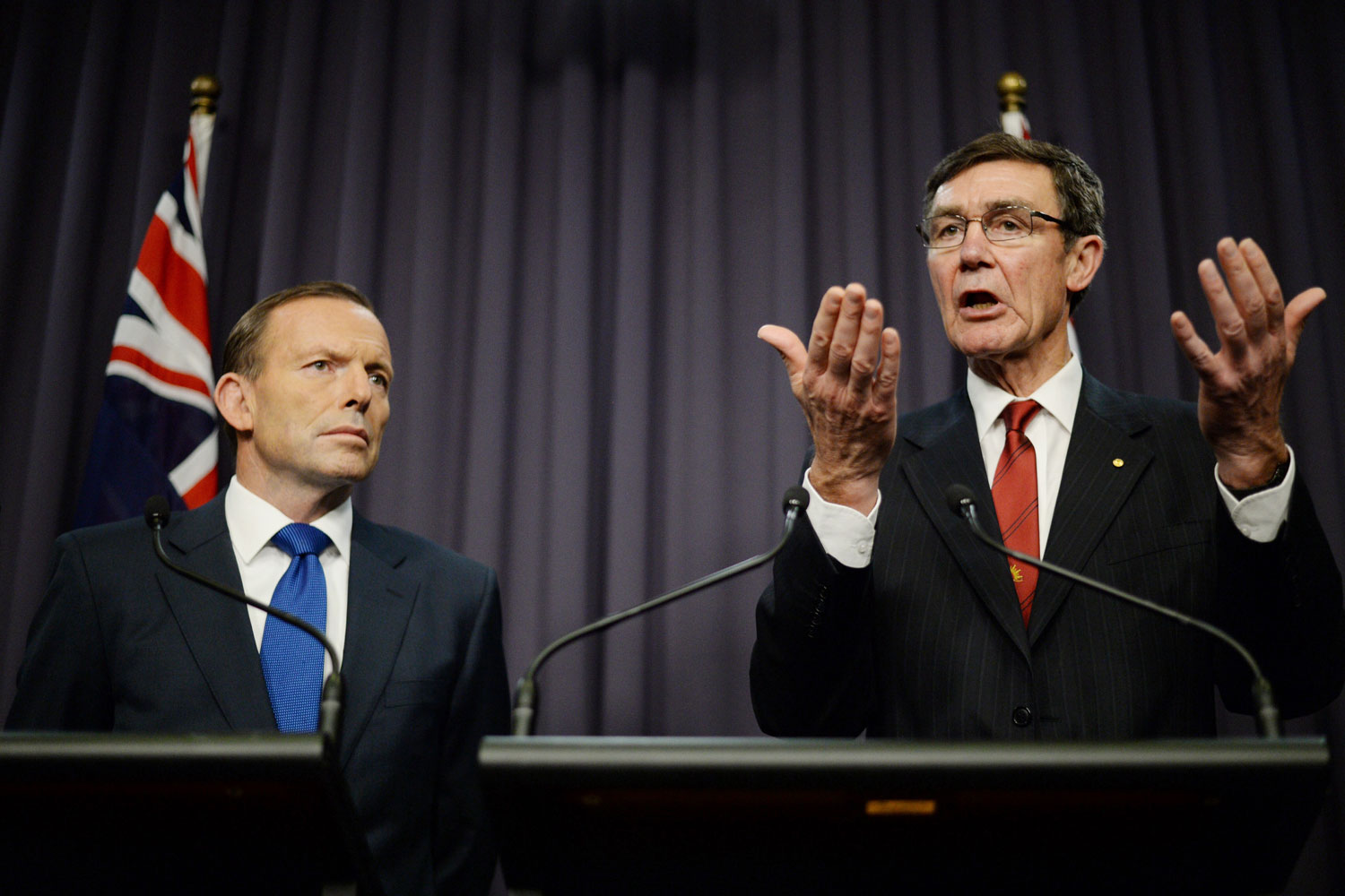 From left: Prime Minister Tony Abbott listens as Angus Houston, in charge of joint search efforts, speaks to the media during a press conference at Parliament House in Canberra on April 28, 2014. (Lukas Coch—AAP/AP)