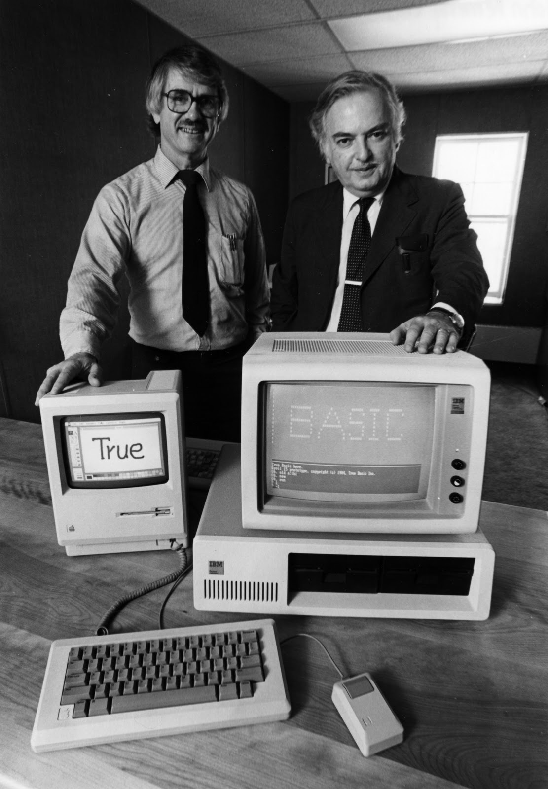BASIC creators Thomas Kurtz (left) and John Kemeny in the mid-1980s, showing their True BASIC running on a Mac and an IBM PC (Dartmouth College)