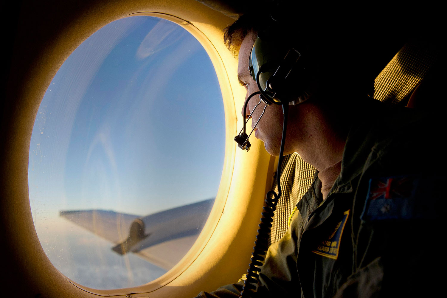 Royal Australian Air Force (RAAF) Airborne Electronics Analyst Sergeant Patrick Manser looks out of an observation window aboard a RAAF AP-3C Orion aircraft during the search in the southern Indian Ocean for debris from the missing Malaysian Airlines flight MH370 in this picture released by the Australian Defence Force April 1, 2014.