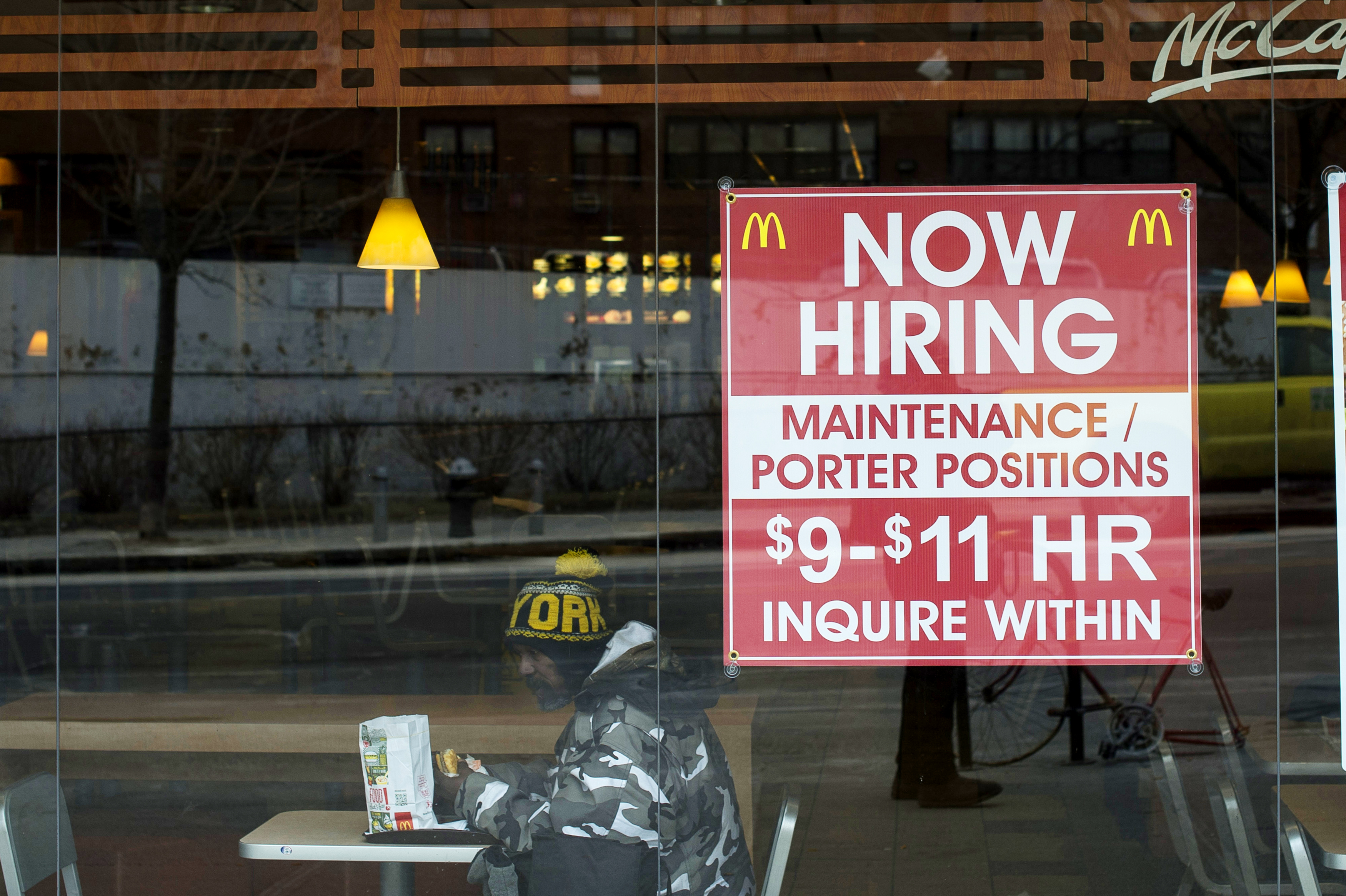 A diner sits next to a help wanted sign at a McDonalds restaurant in the Brooklyn borough of New York, on March 7, 2014.