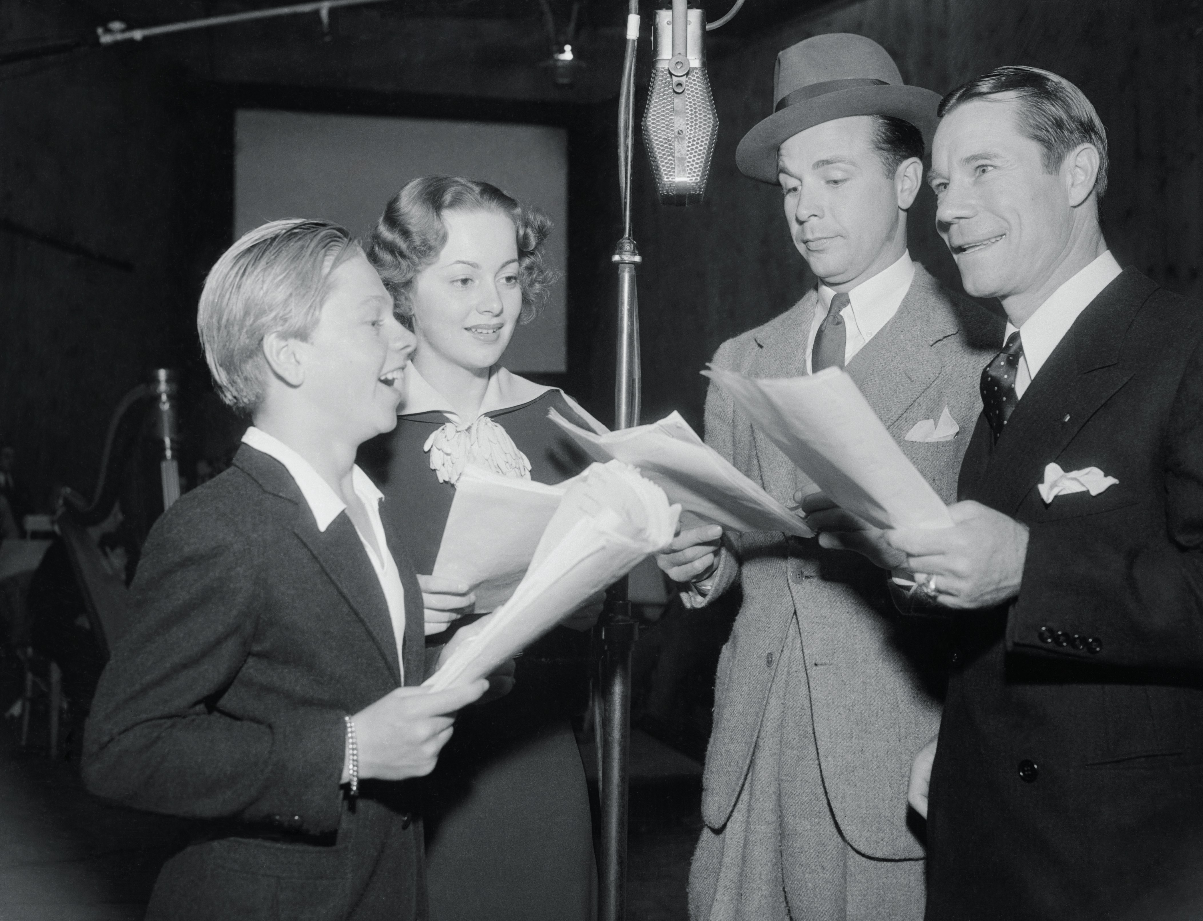 From left: Mickey Rooney, Olivia De Havilland, Dick Powell and Joe E. Brown under the microphone at the nation-wide broadcast from Los Angeles of A Midsummer Night's Dream on Oct. 10, 1935, in Los Angeles.