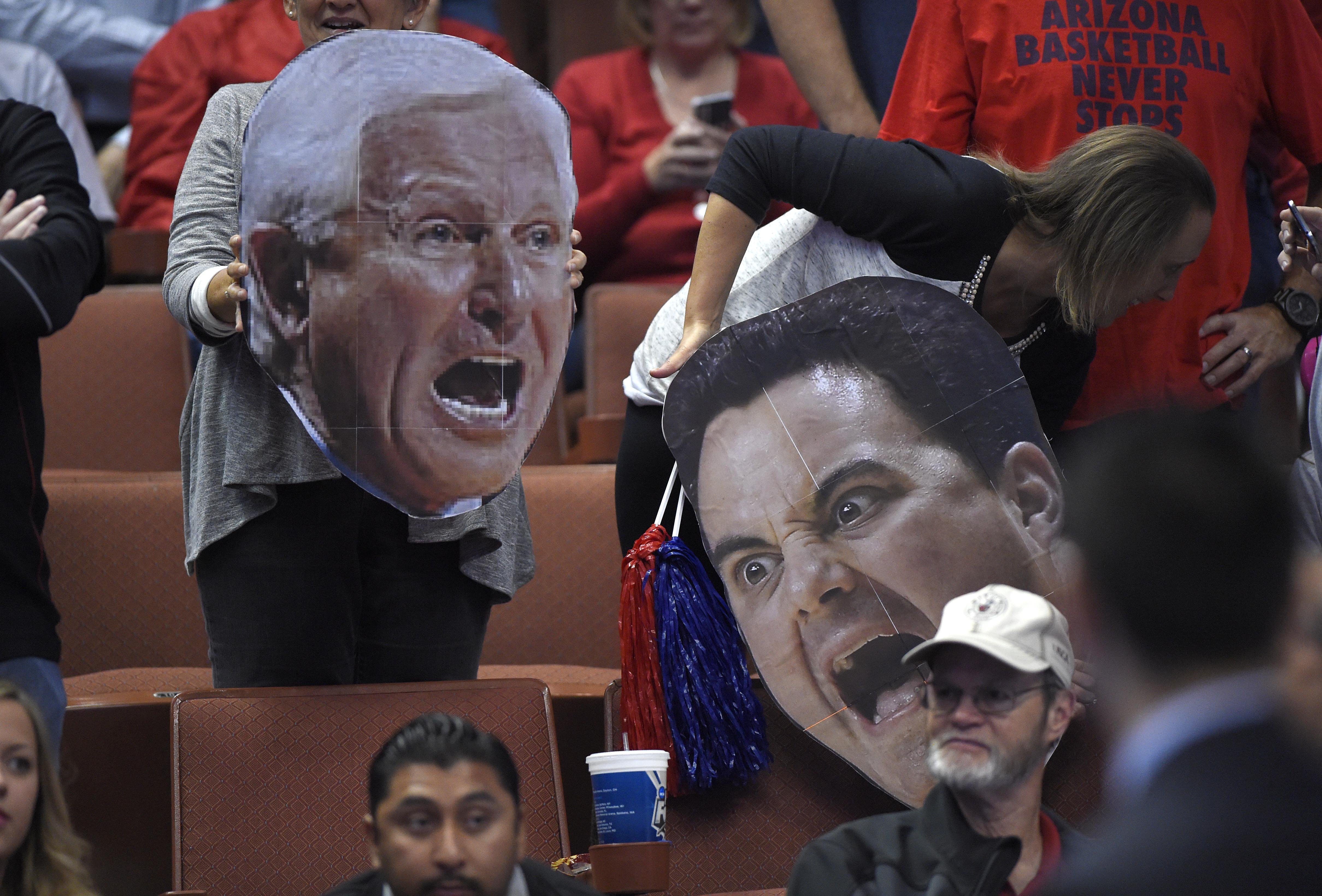 Arizona fans hold cutouts of former coach Lute Olsen, left, and current head Sean Miller prior to a regional semifinal NCAA college basketball tournament game, March 27, 2014, in Anaheim, Calif.