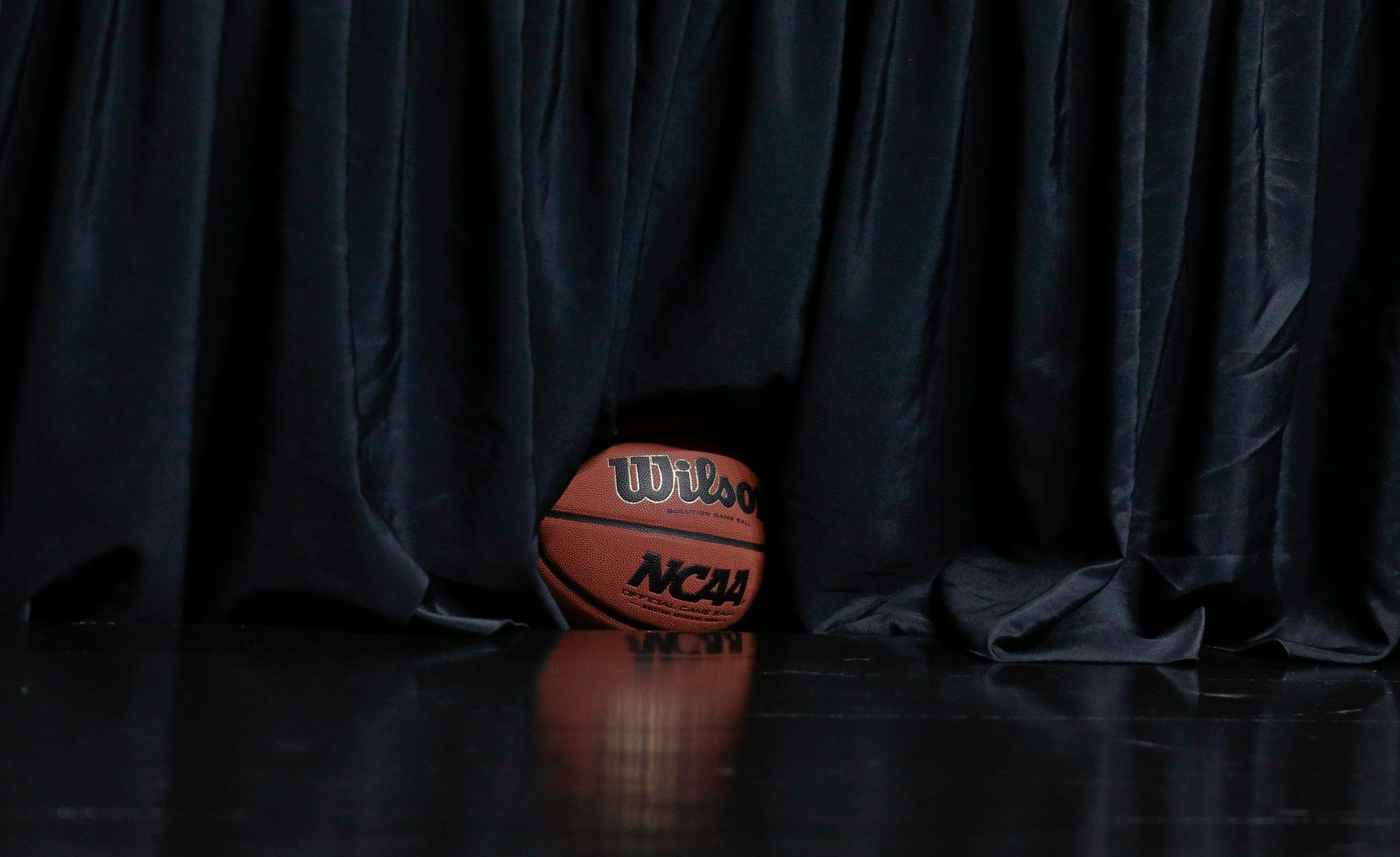 A NCAA tournament basketball sits under a curtain at court side before a third round game between UCLA and Stephen F. Austin at the NCAA college basketball tournament, March 23, 2014, in San Diego.