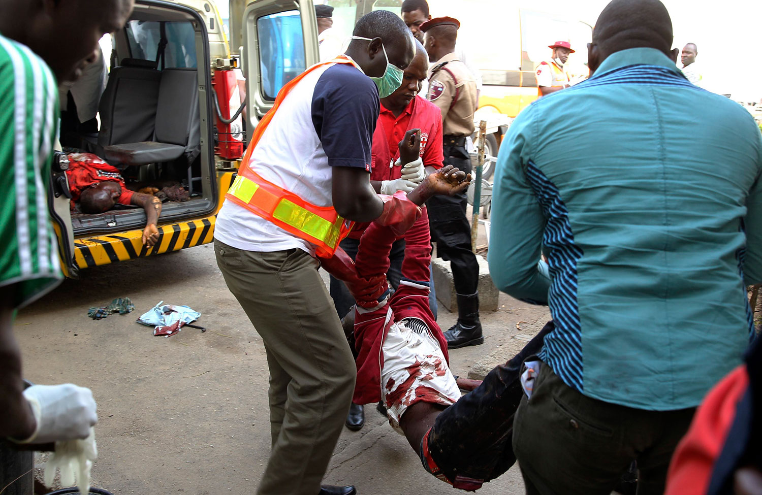 A Red Cross worker and other volunteers help move a body into the mortuary of the Asokoro General Hospital after a bomb blast, in Abuja, April 14, 2014.
