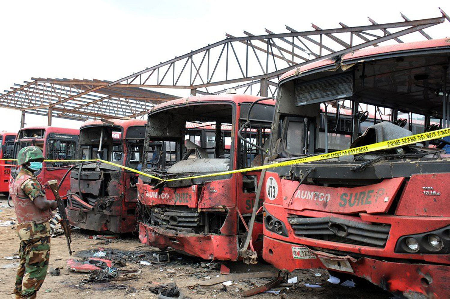 A soldier stands guard in front of burnt buses after an attack in Abuja, on April 14, 2014.