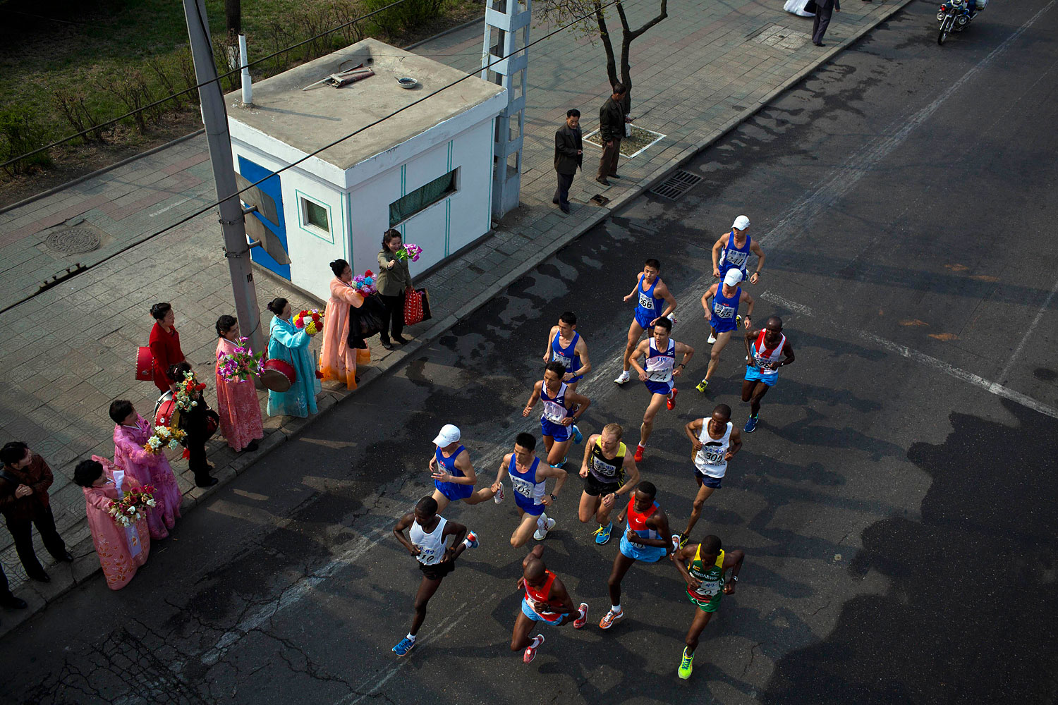 The lead pack of runners are cheered on by North Korean spectators on the roadside in central Pyongyang during the running of the Mangyongdae Prize International Marathon in Pyongyang on April 13, 2014.