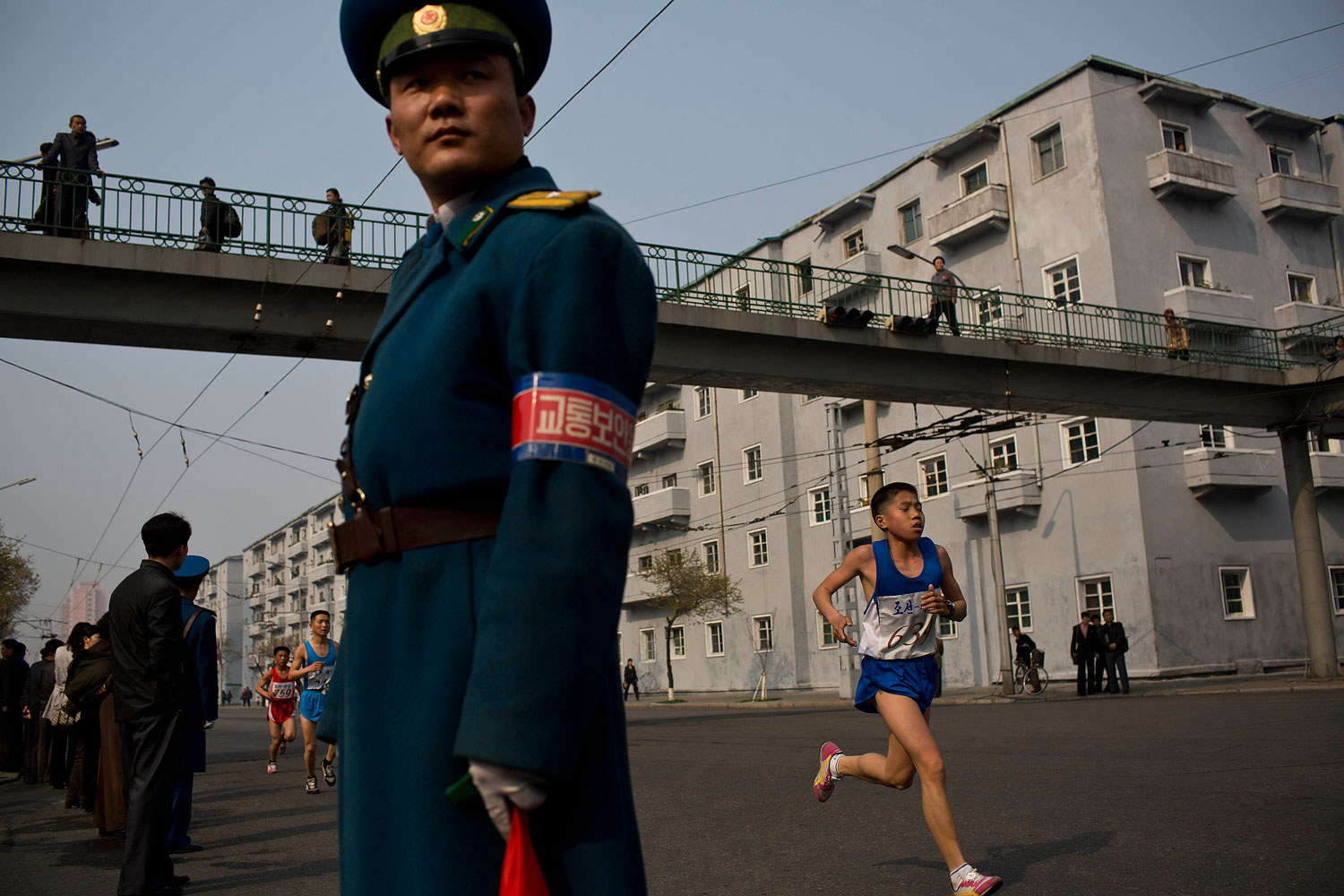 Runners pass under a pedestrian bridge in central Pyongyang during the running of the Mangyongdae Prize International Marathon in Pyongyang, on April 13, 2014.