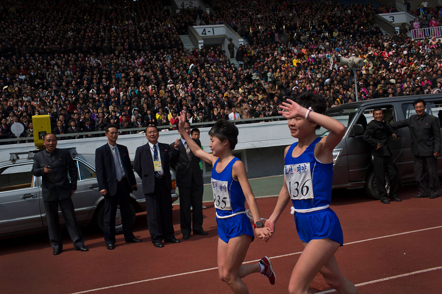 North Korean twin sisters Kim Hye Gyong (135) and Kim Hye Song (136) take a victory lap together inside Kim Il Sung Stadium after placing first and second respectively in the the women's Mangyongdae Prize International Marathon in Pyongyang, on April 13, 2014.