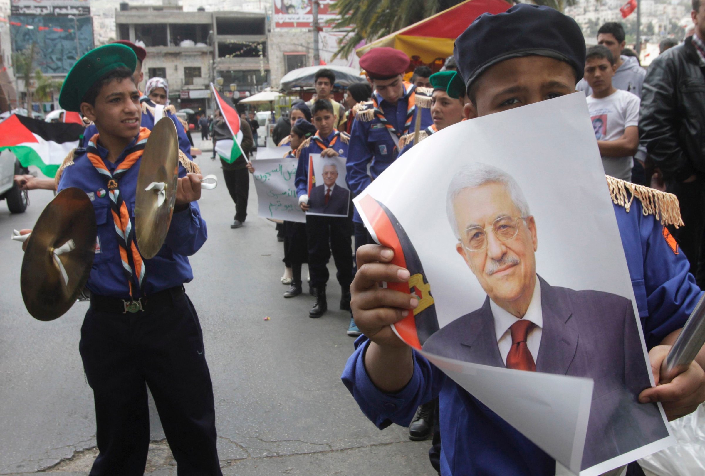 Palestinian scouts hold posters of Palestinian President Mahmoud Abbas during a Fatah rally in support of Abbas in the West Bank city of Nablus on April 2, 2014.