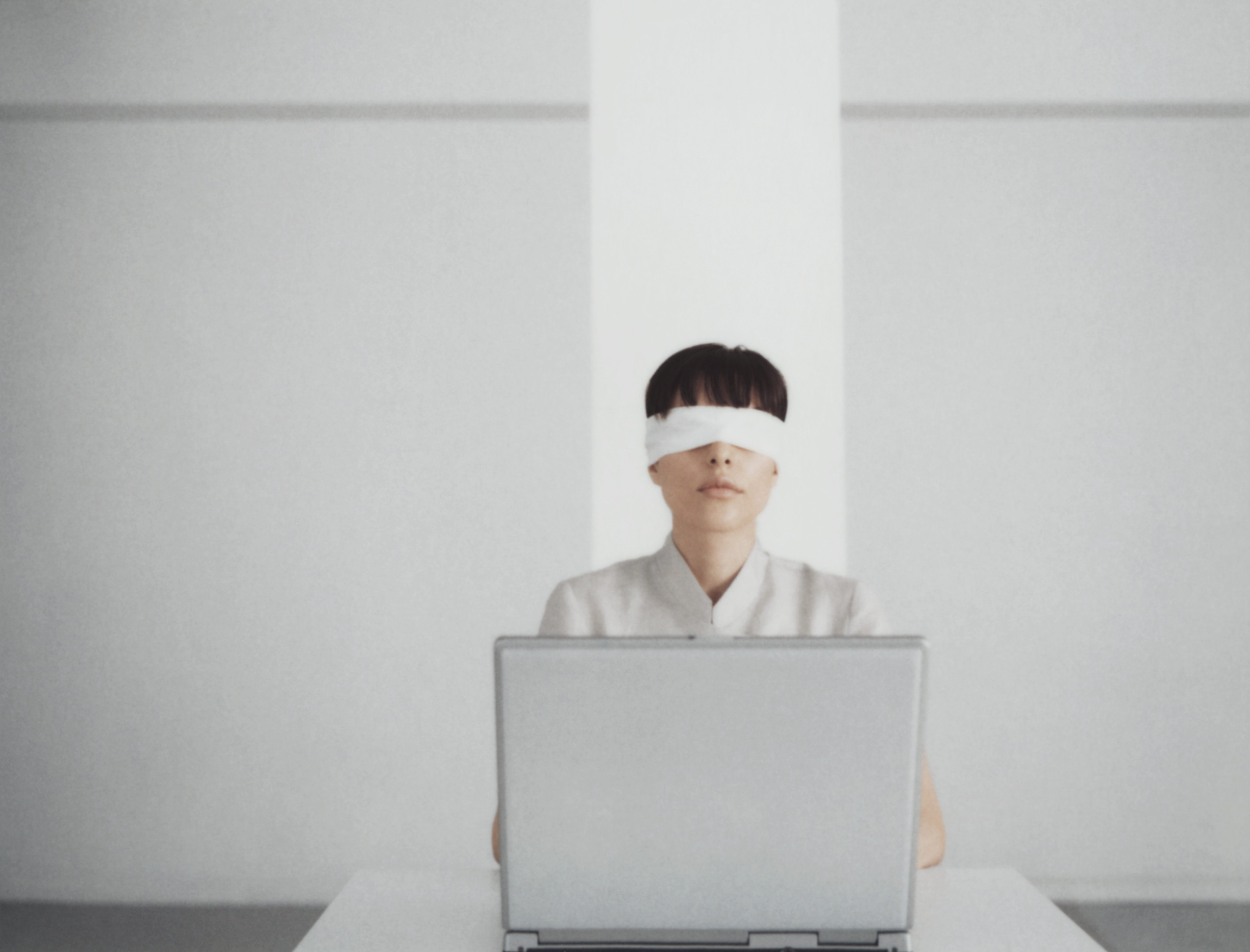 Blindfolded woman sitting behind laptop (Getty Images)