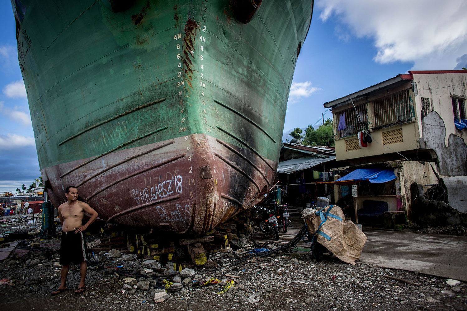 A man stands in front of a large ship grounded by Typhoon Haiyan on April 18, 2014 in Tacloban, Leyte, Philippines,