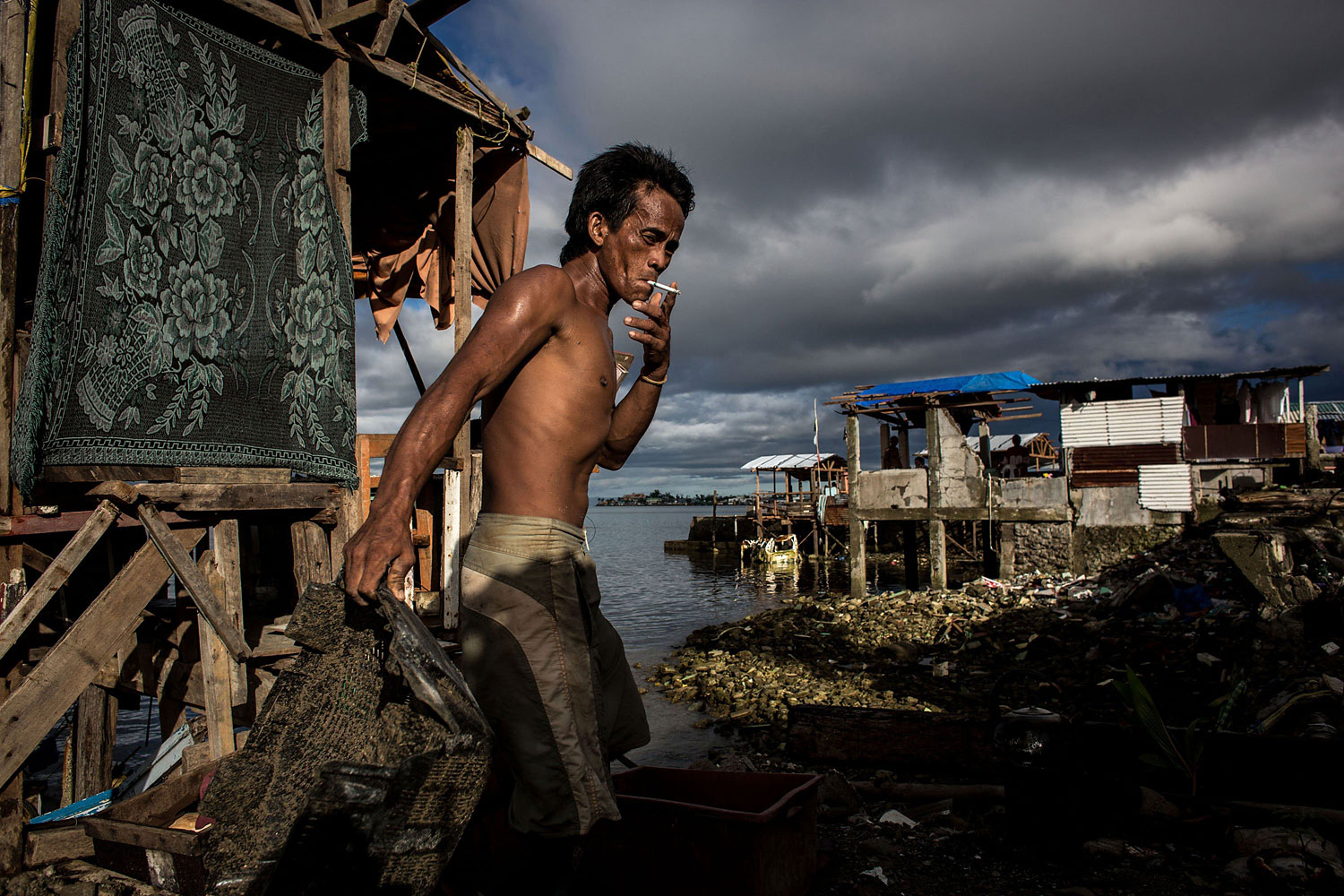 A man smokes as he removes rubble from his home on April 18, 2014 in Tacloban.