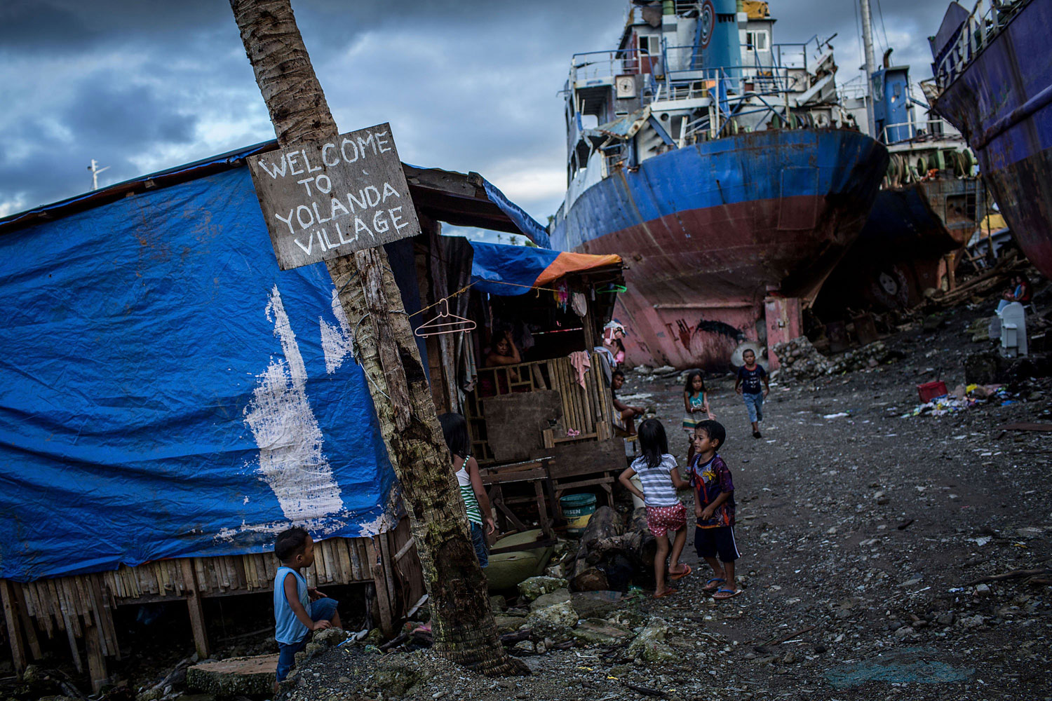 Children play around three large ships grounded by Typhoon Haiyan on April 18, 2014 in Tacloban.