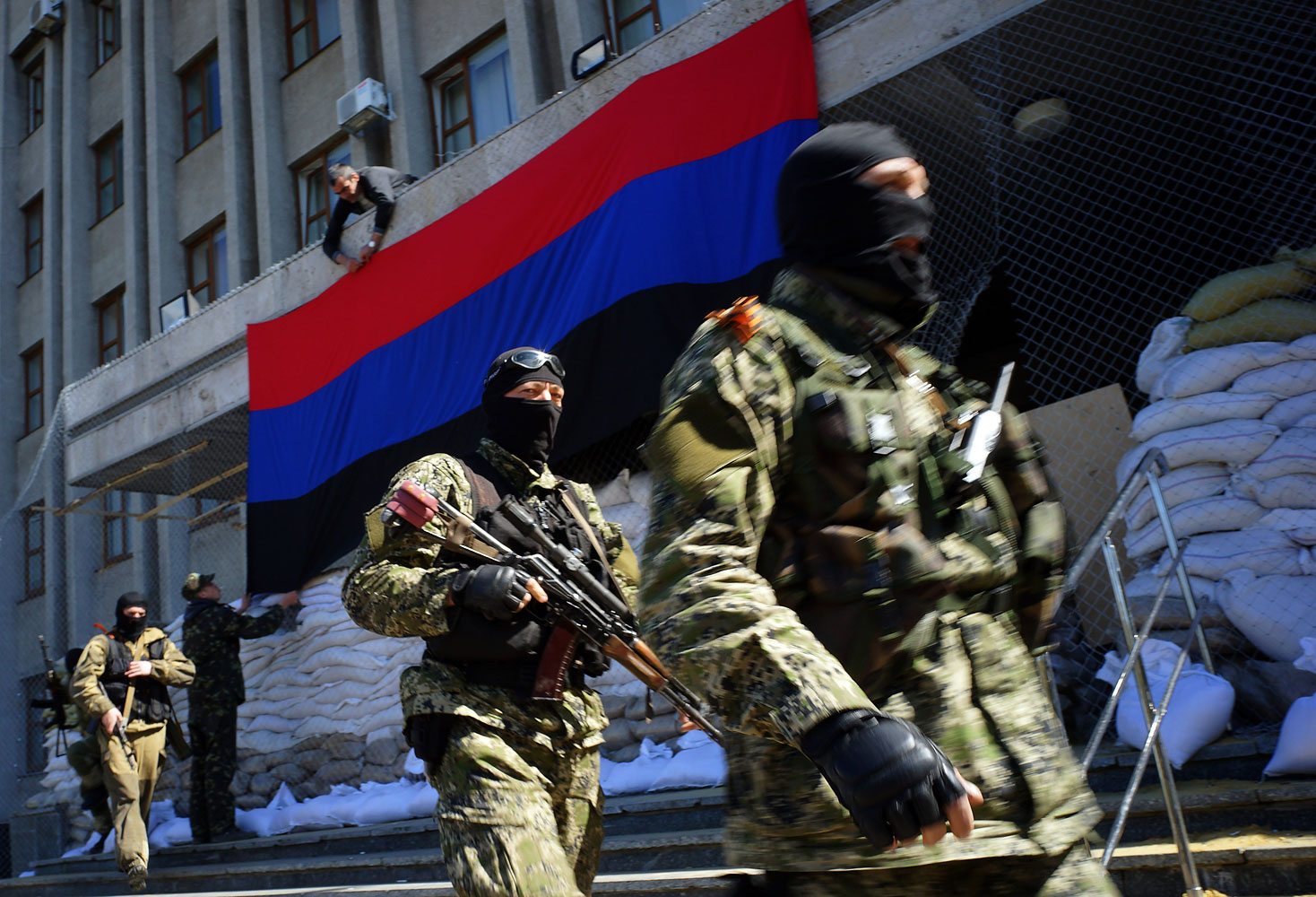 A pro-Russia activist hangs a flag of the so-called "People's Republic of Donetsk" on the regional administration building seized by separatists as armed men in military fatigues guard the premises in the eastern Ukrainian city of Slavyansk on April 21, 2014. (Genya Savilov—AFP/Getty Images)