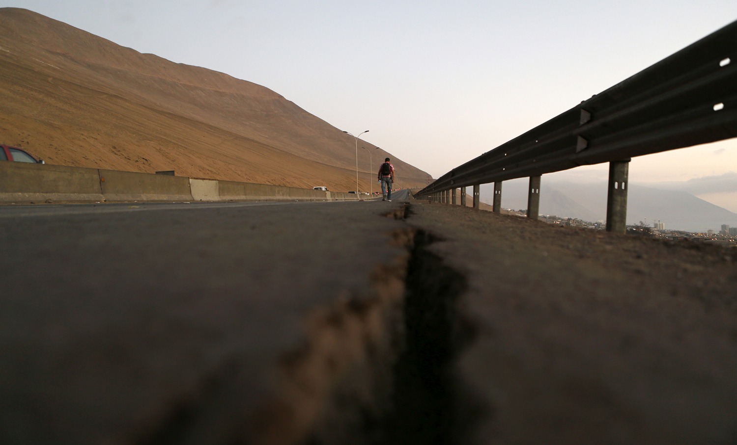 A resident walks along a damaged road after an earthquake and tsunami hit the northern port of Iquique