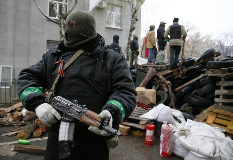 An armed man stands next to a barricade in front of the police headquarters in Slaviansk